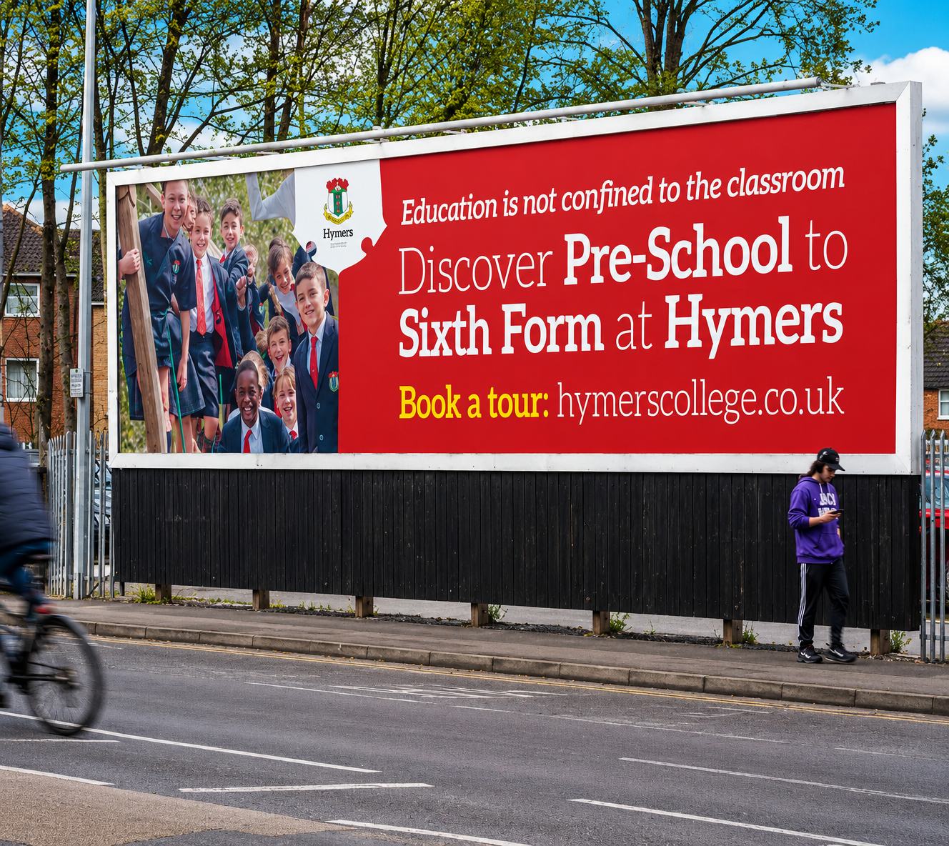 Billboard advertising Hymer's college with a photo of smiling students in school uniforms and logo, highlighting pre-school to sixth form education, and encouraging booking a tour at hymerscollege.co.uk.
