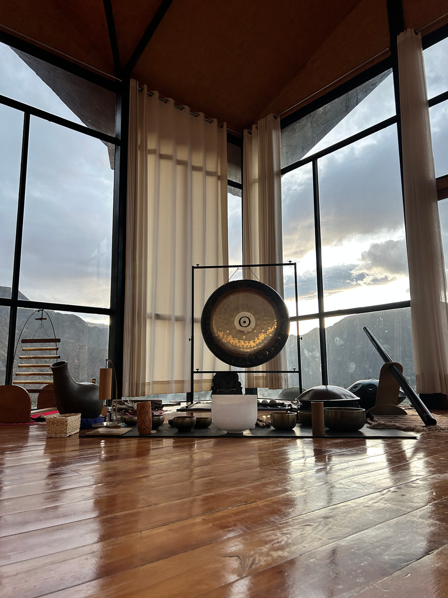 Sound instruments including gongs and bowls and mallets set to a beautiful mountain backdrop.