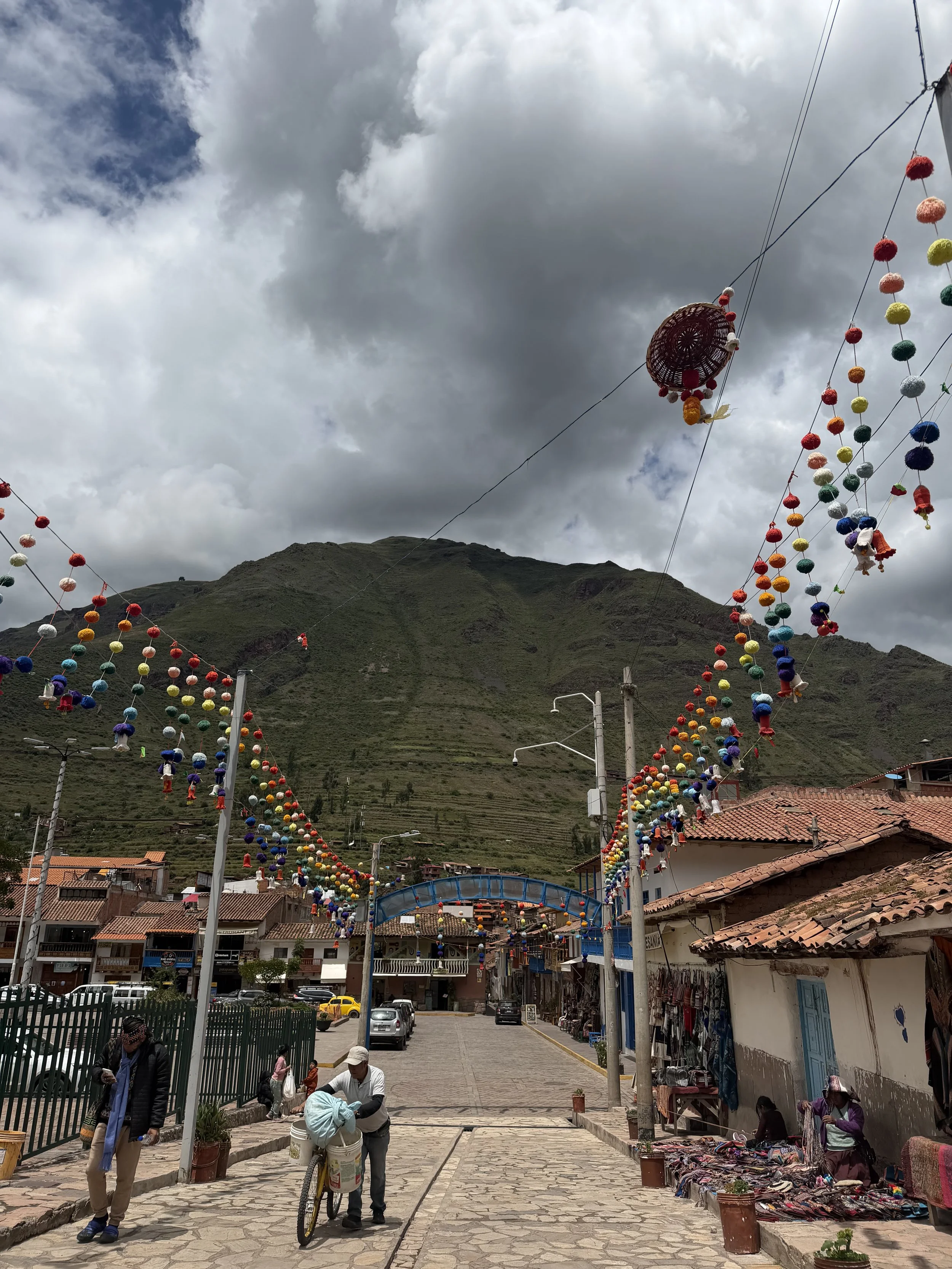A colorful Peruvian town with rainbow fabric string decor, tiled roofs and cobble stone streets.