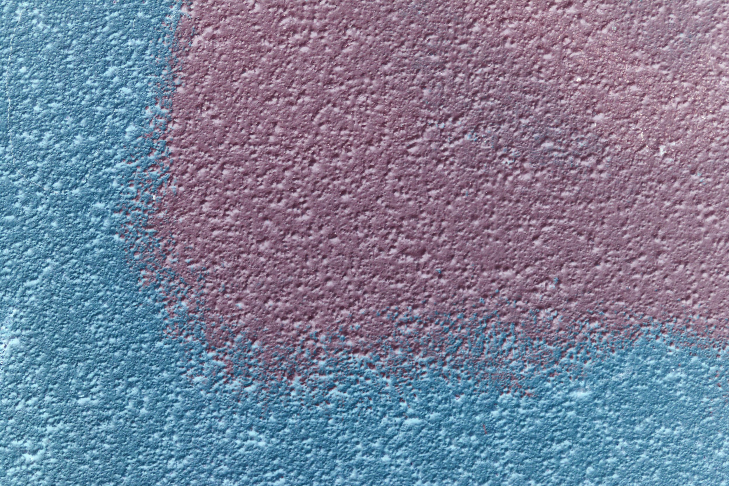 Close-up of a textured surface with a pinkish tone, showing small bumps and roughness, illuminated with pink and blue lighting.