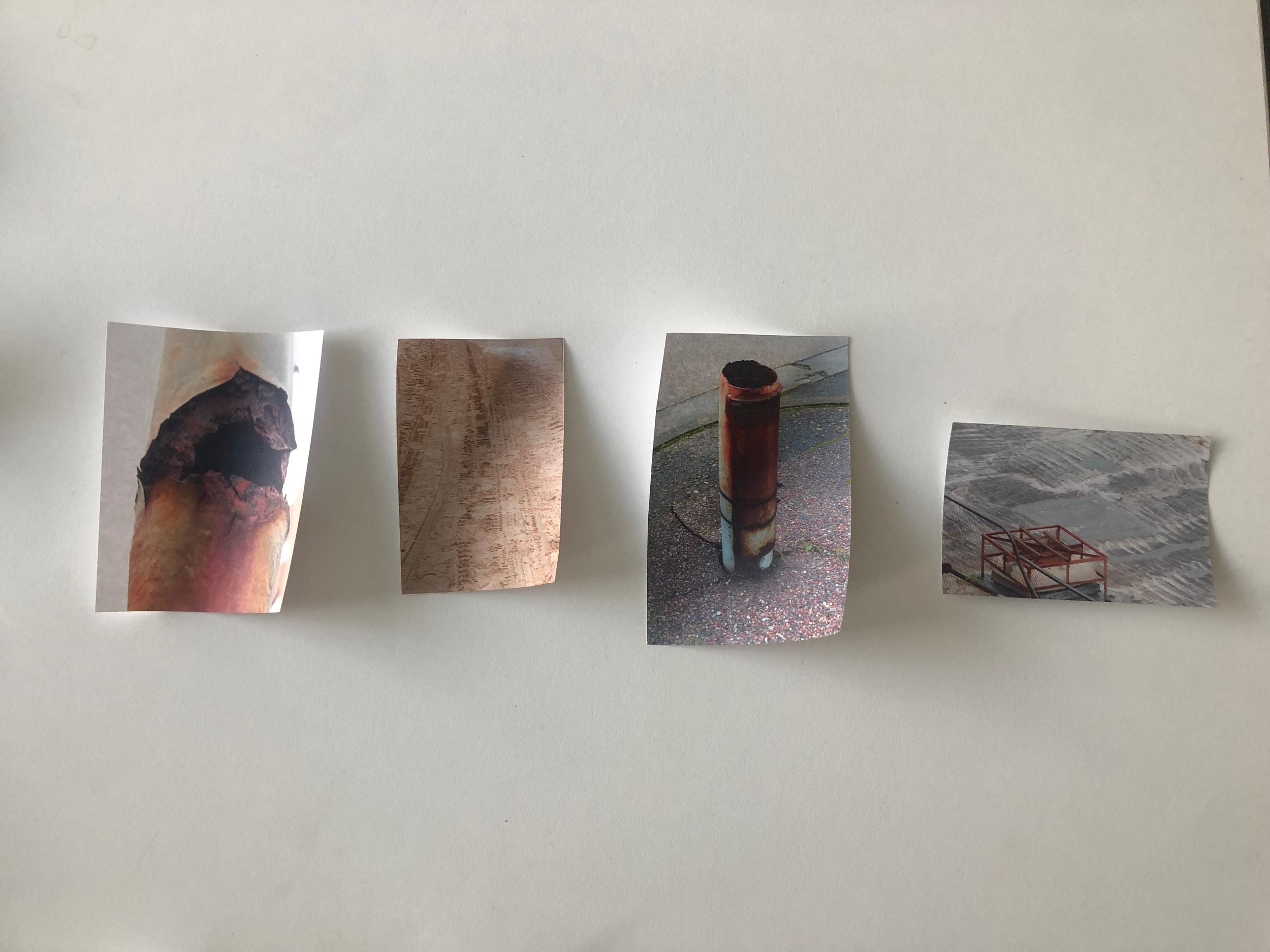 Collection of small photographs featuring various objects, including a rusted pipe and a metal box, arranged on a white surface.