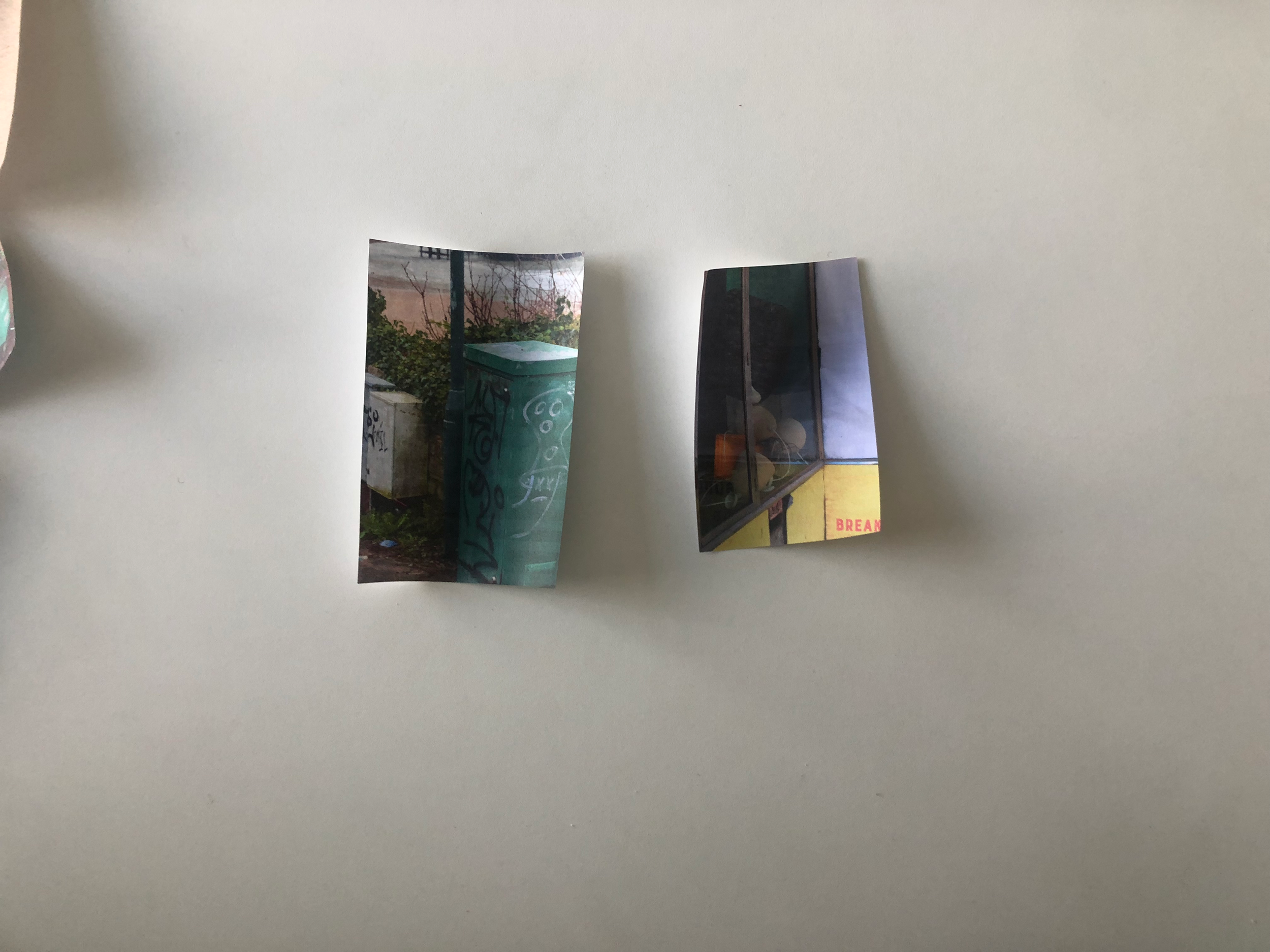 Three small printed photographs attached to a white surface, showcasing outdoor scenes and a building interior.