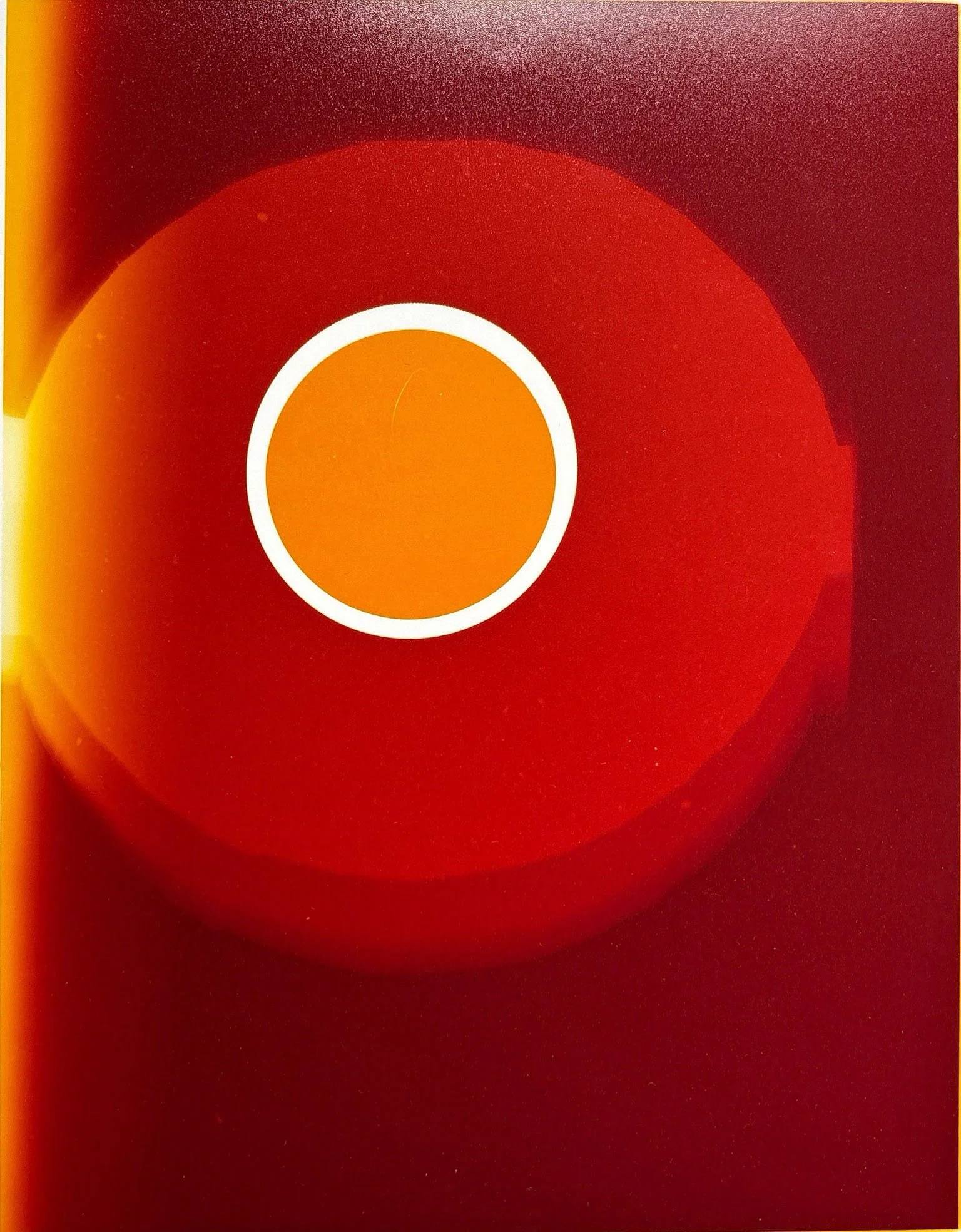 Abstract artwork featuring a yellow, red, and orange color gradient with a central white circle surrounded by a red ring.