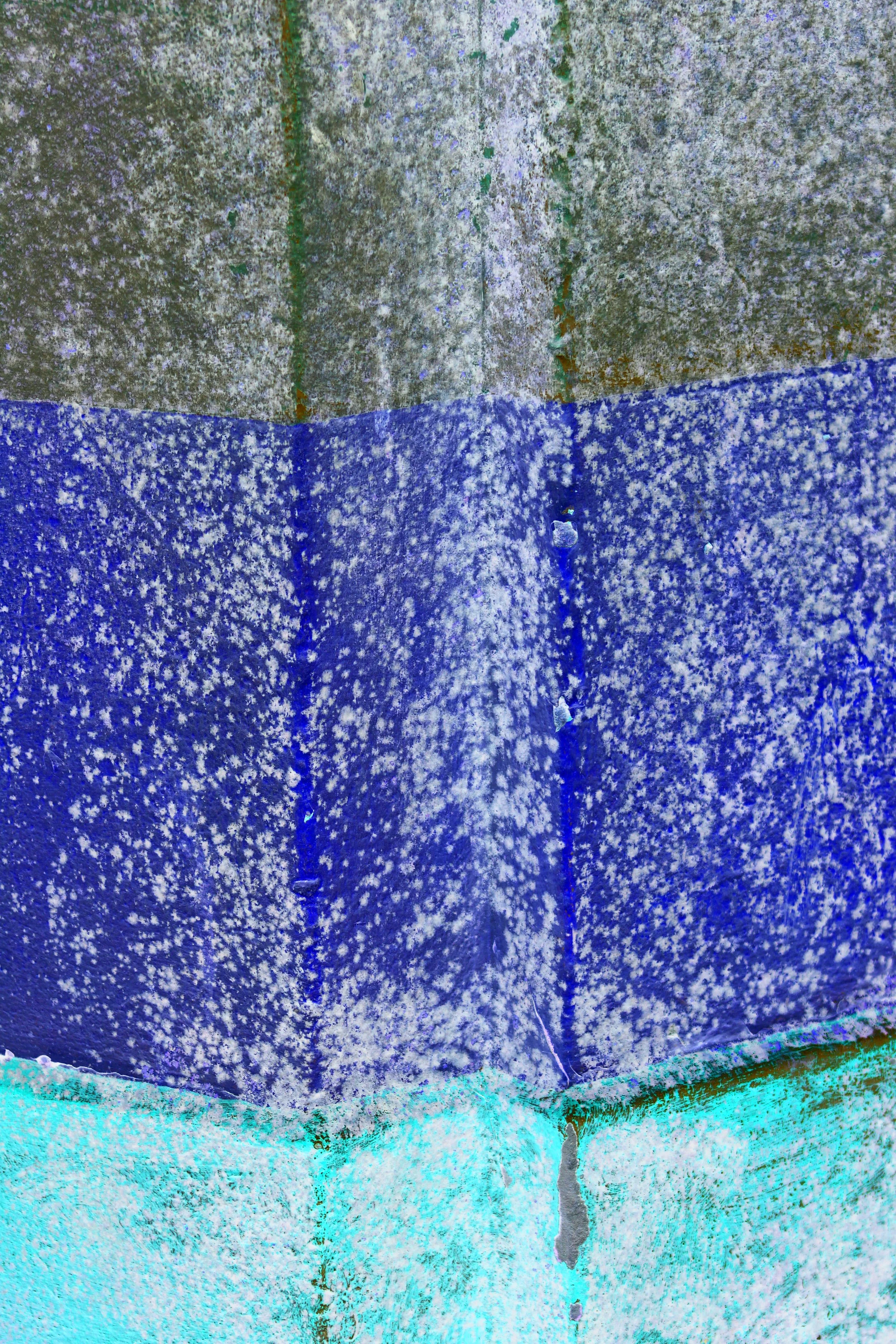Close-up image of three overlapping paper layers with textured, speckled patterns in shades of blue, gray, and turquoise.