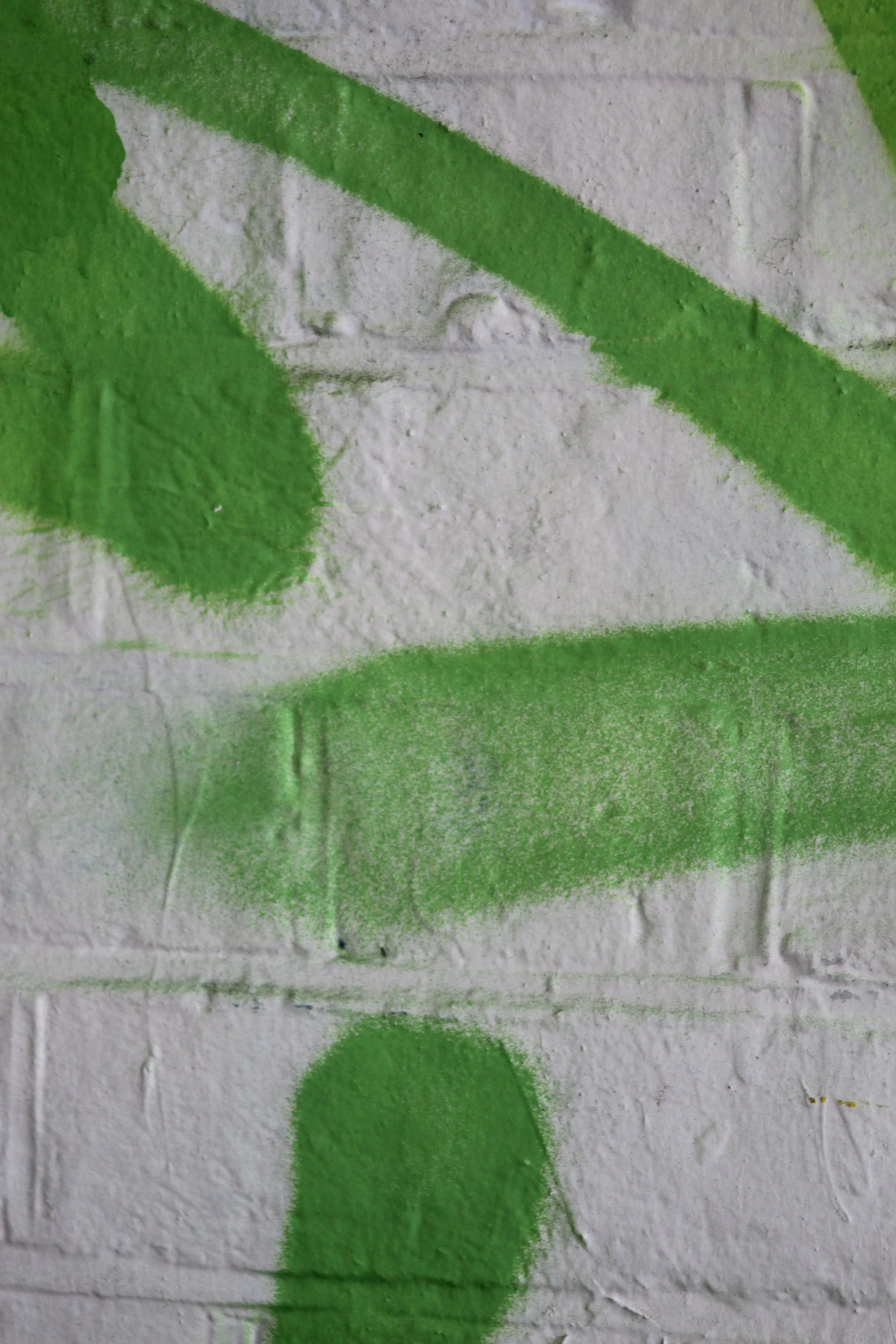 Close-up of a white brick wall with green spray paint design.