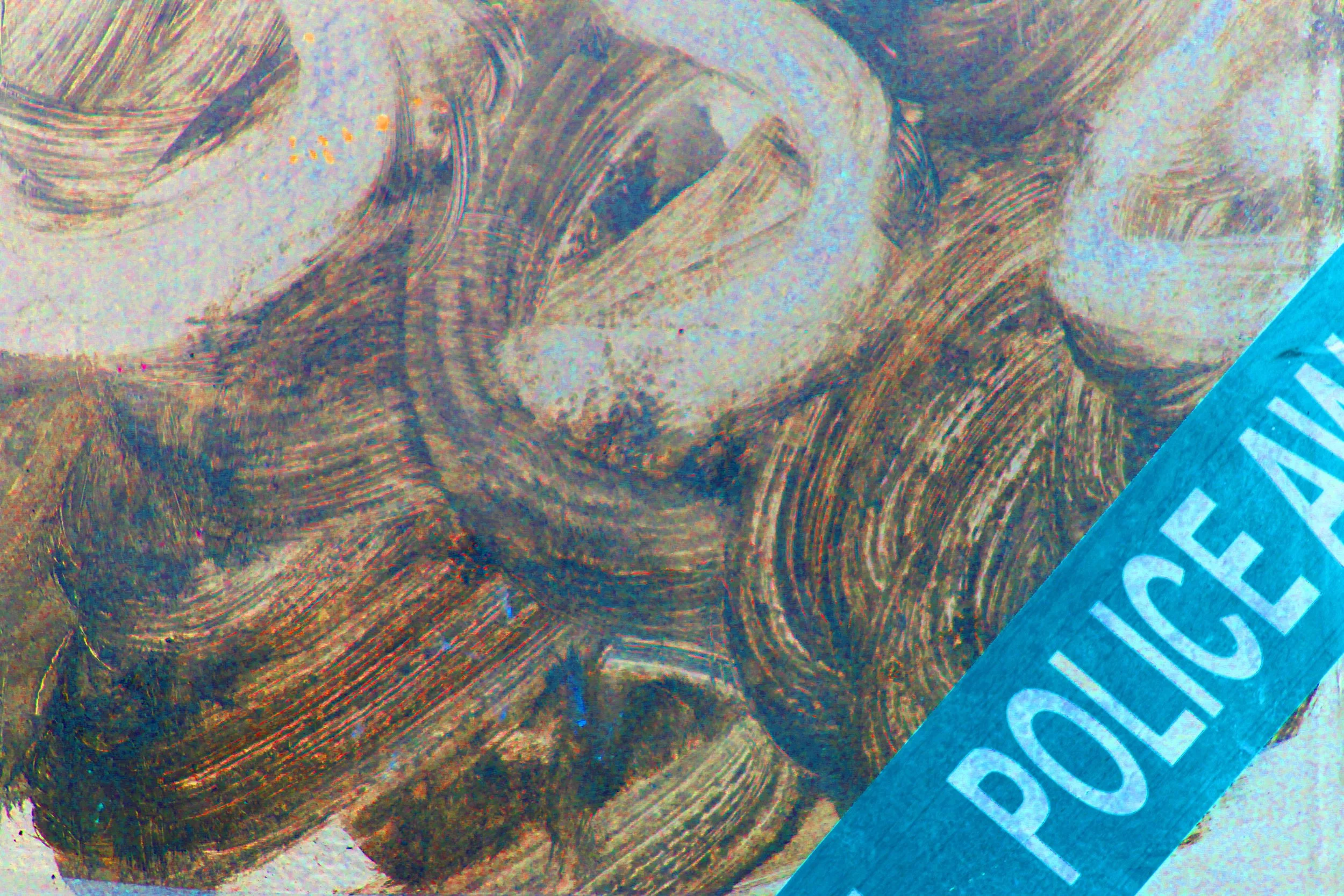 Close-up of a banknote with intricate line patterns and a blue strip with partially visible white text.