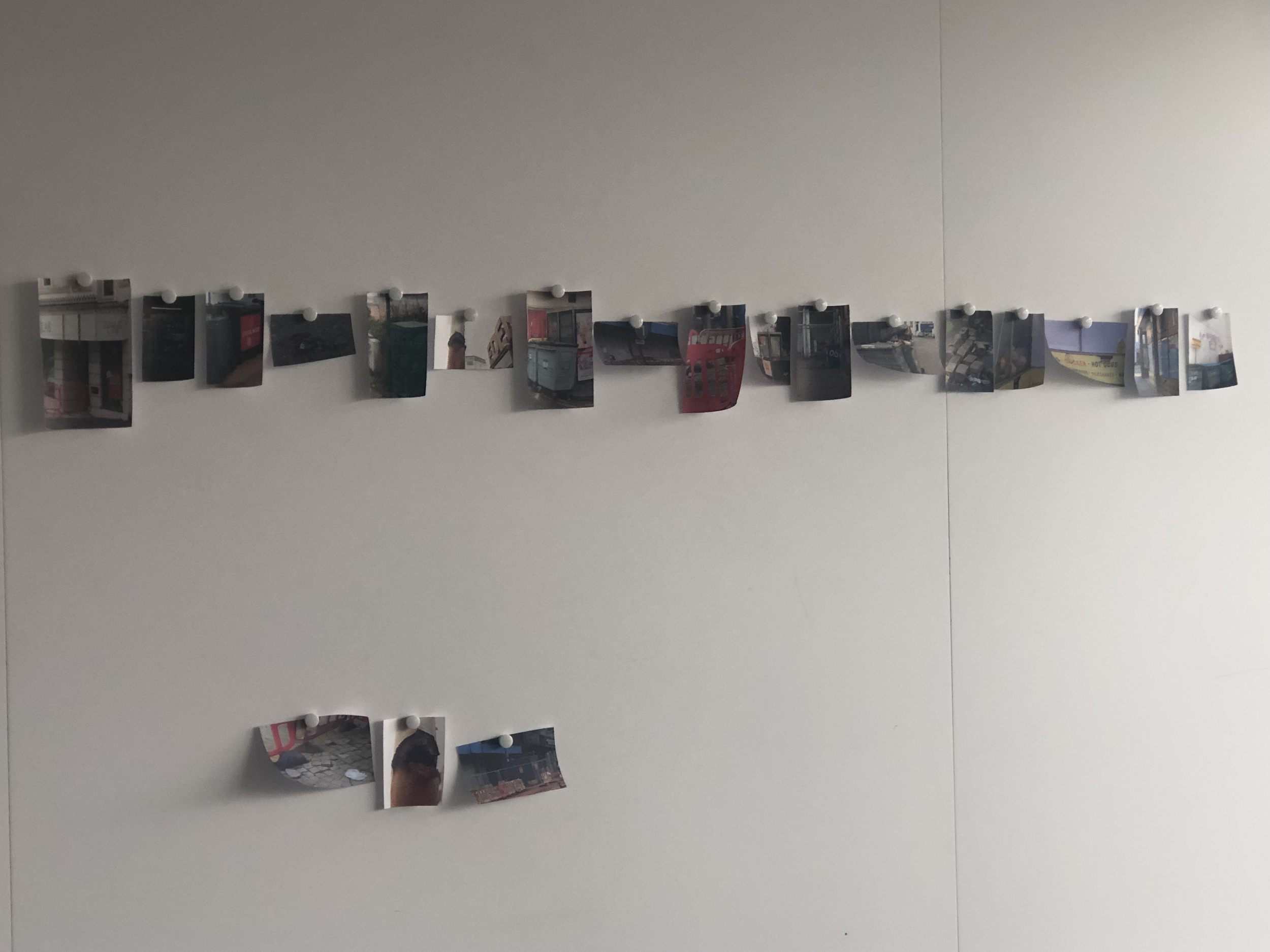 Photo of small printed photographs pinned along a string on a plain wall.