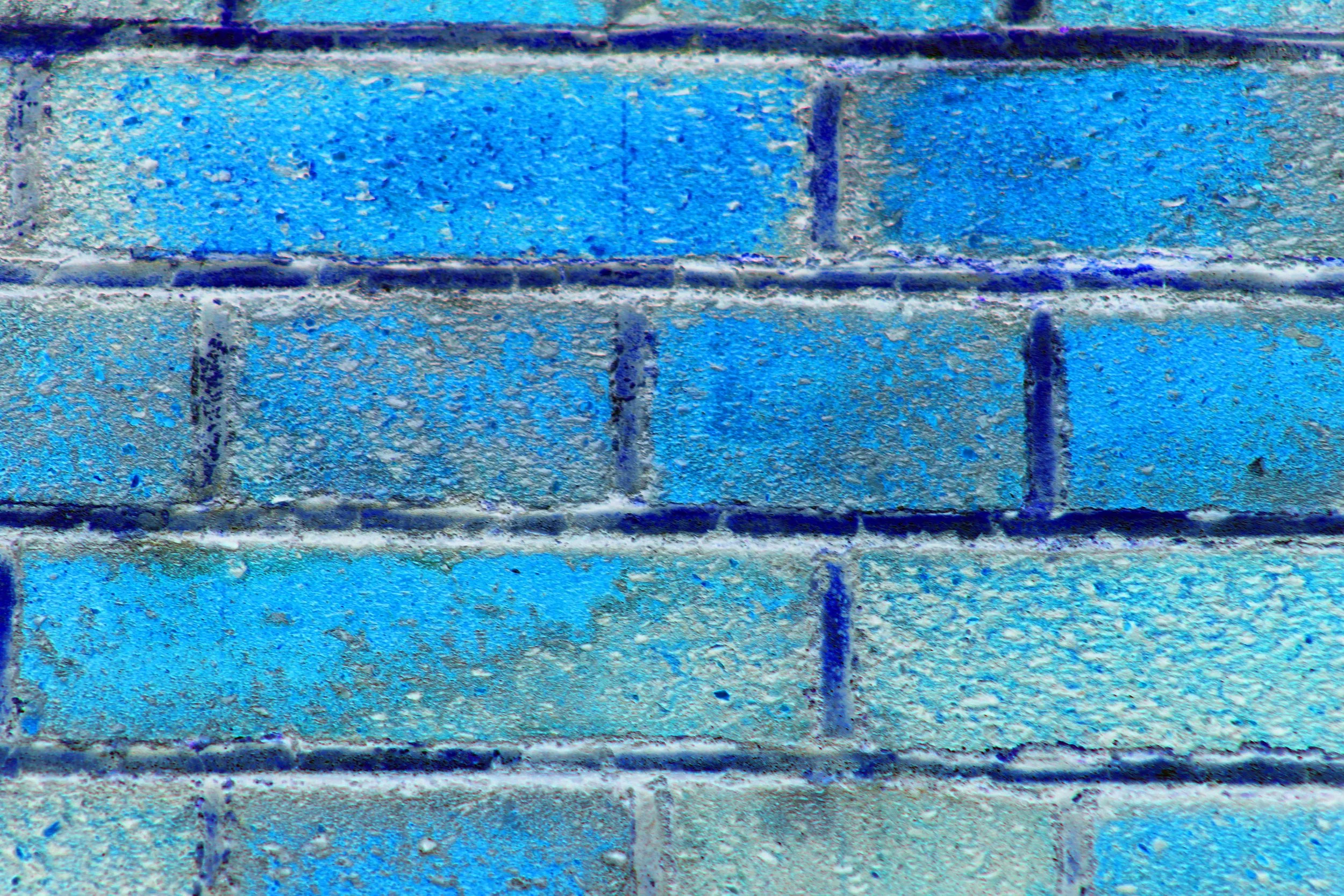 Close-up of a blue painted brick wall with textured surface and visible mortar lines.
