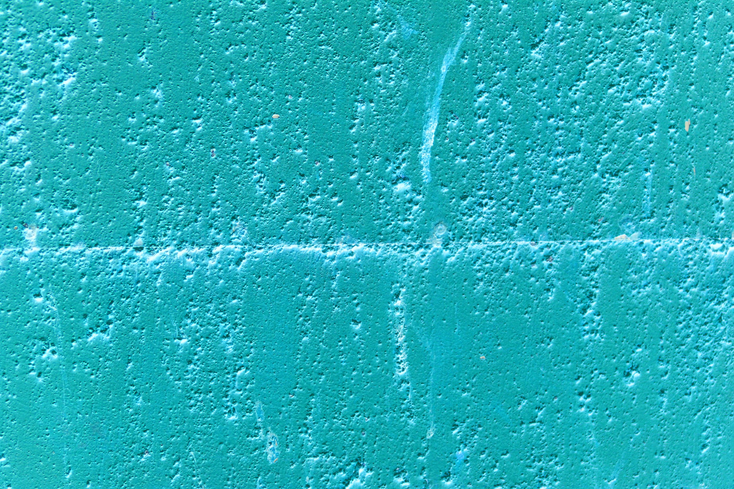 Close-up of a textured turquoise wall with small bumps and irregularities.