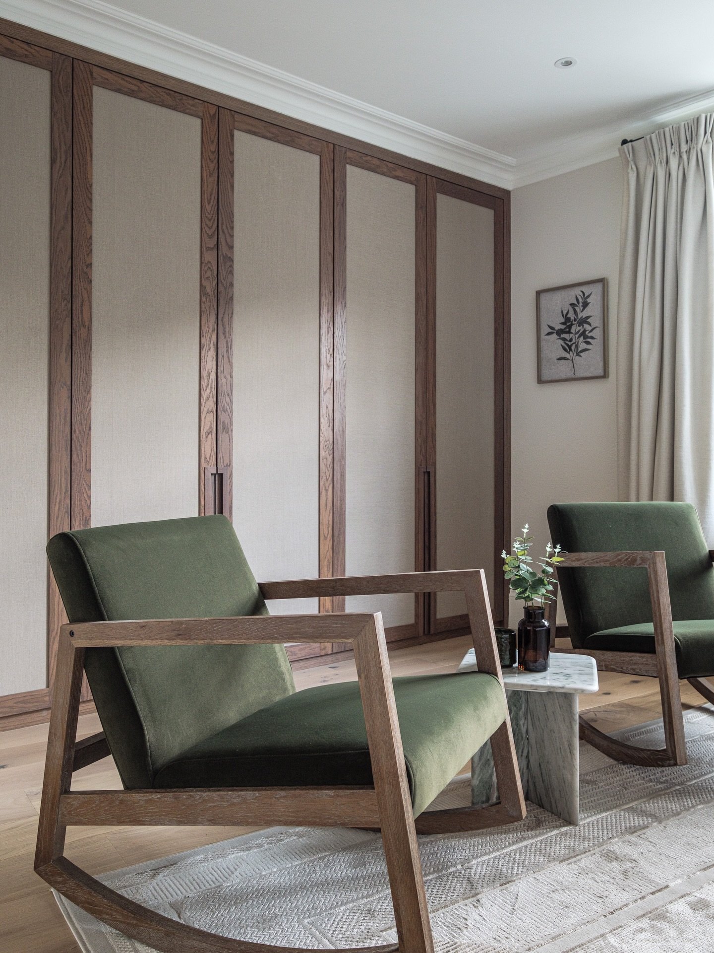 Full height wardrobes with linen insets create a calm architectural backdrop, paired with sculptural rocking chairs in olive velvet. Natural stone, layered neutrals and quiet detailing make this corner feel effortless but intentional.

A lesson in re