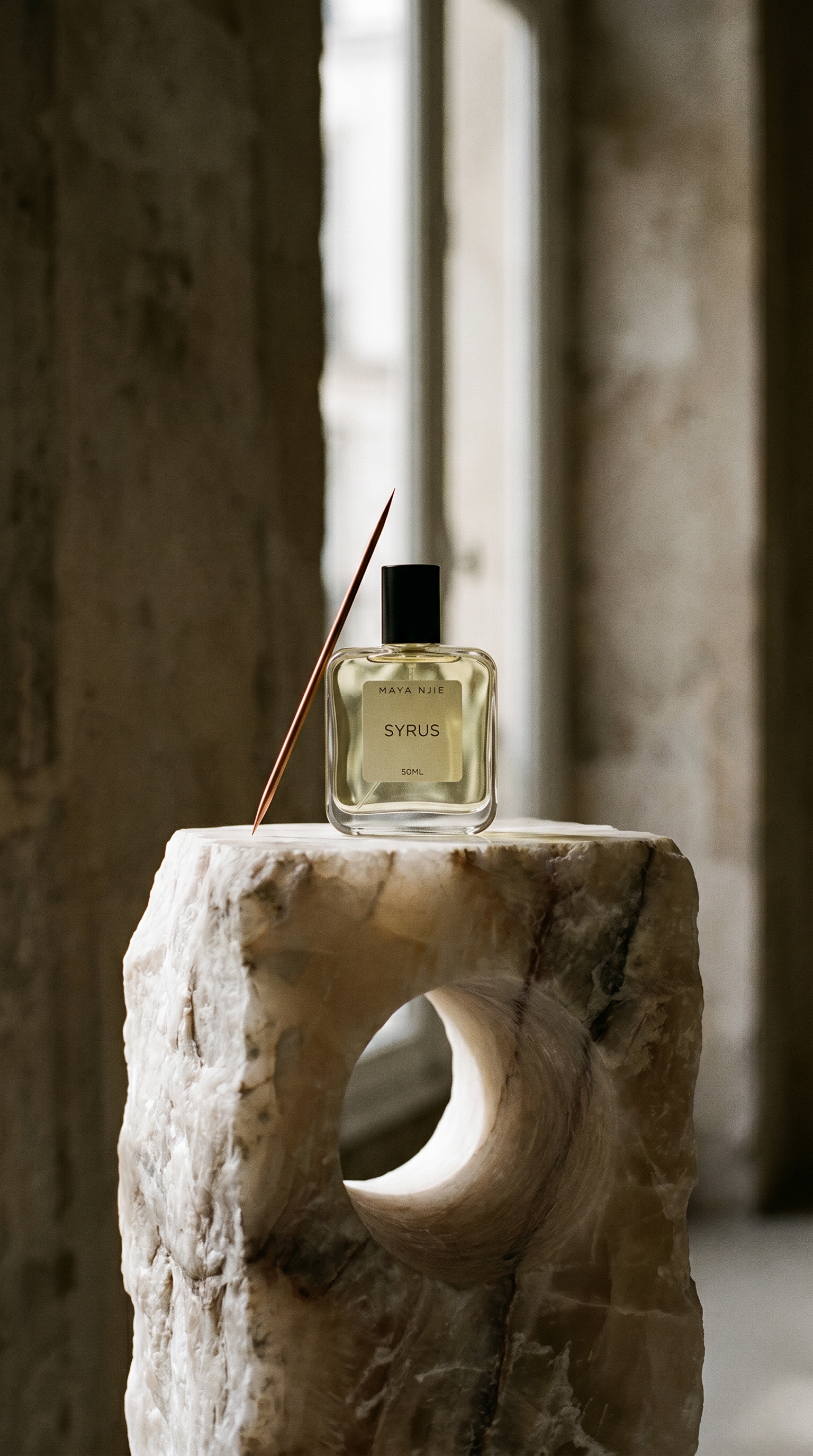 A fragrance bottle resting on a marble monolith with a needle resting against its edge
