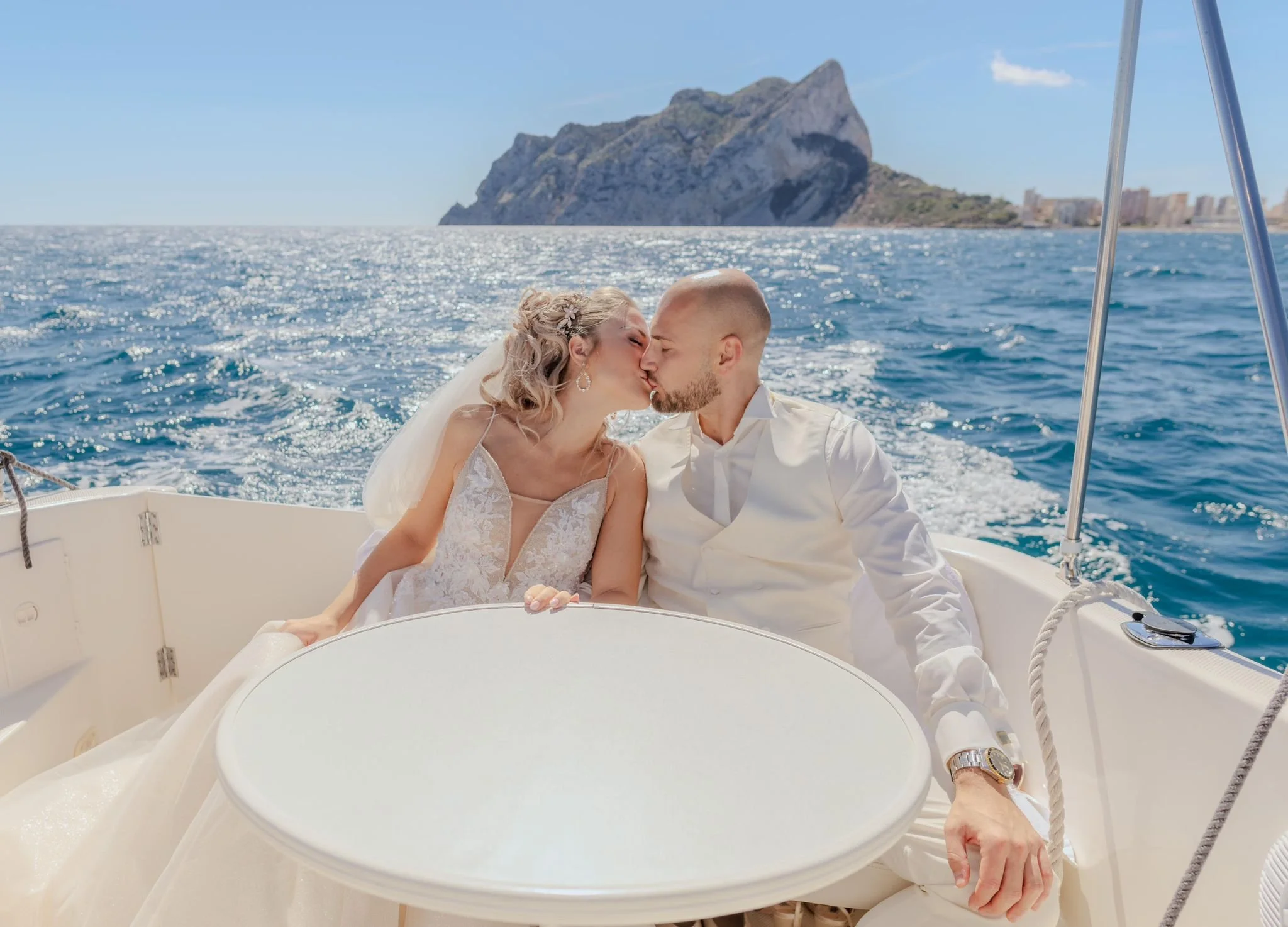 Bride and groom leaving their Costa Blanca wedding venue by speedboat with Calpe Rock in the background