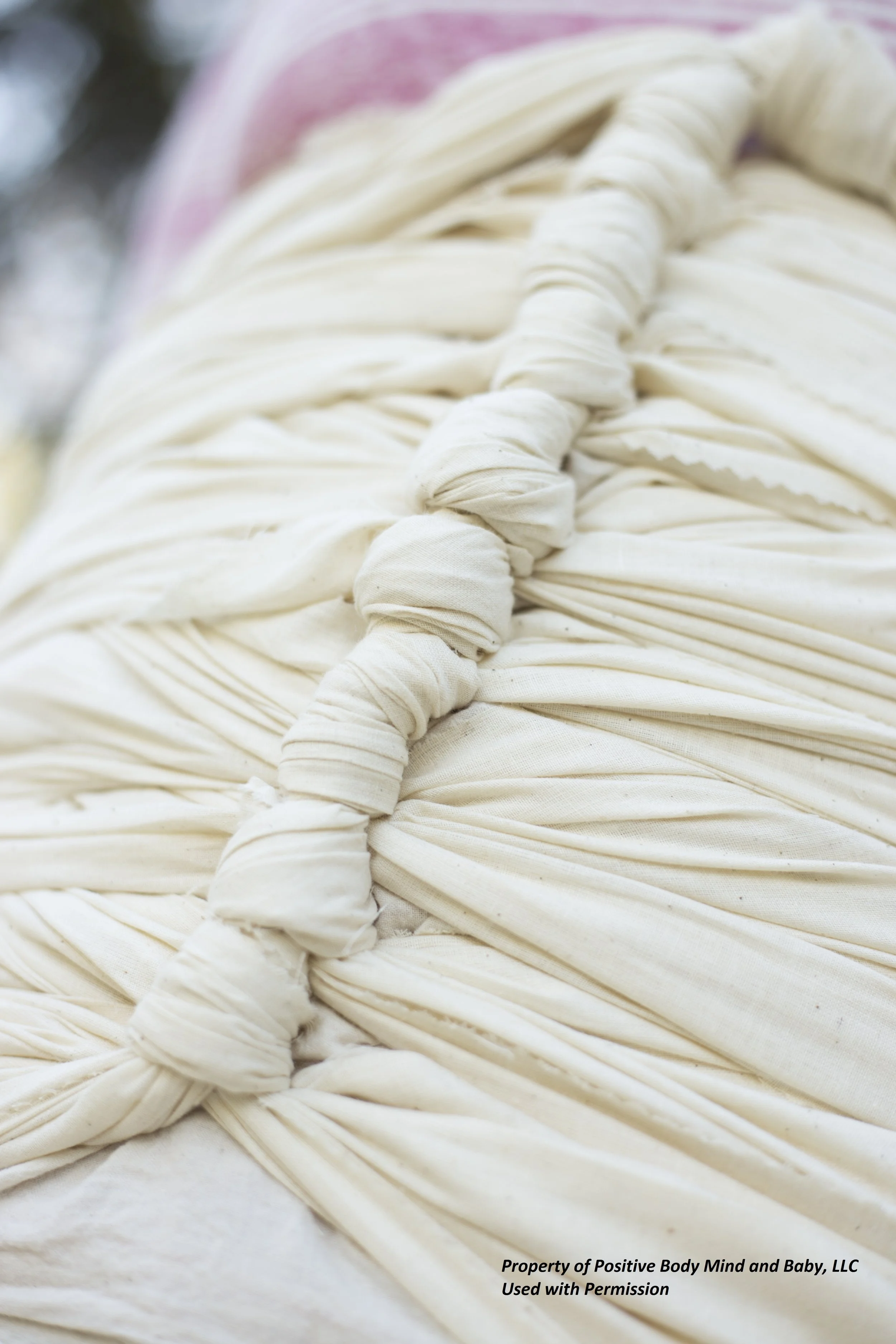 Close-up of a person wearing a white fabric hood or head covering with a twisted knot at the front.