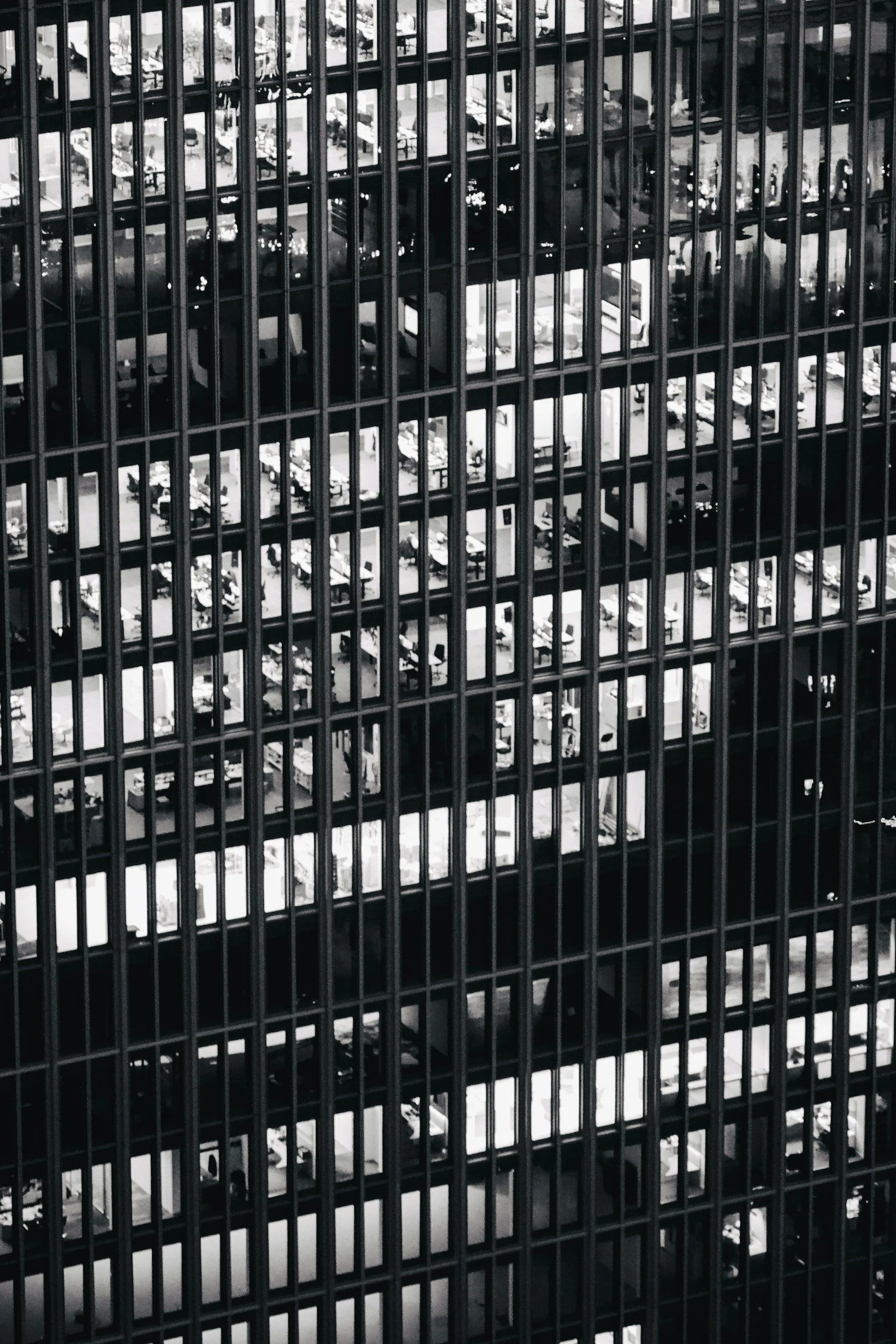 View of the interior of a multi-story parking garage through a grid of metal bars, with a variety of parked cars visible on multiple levels.