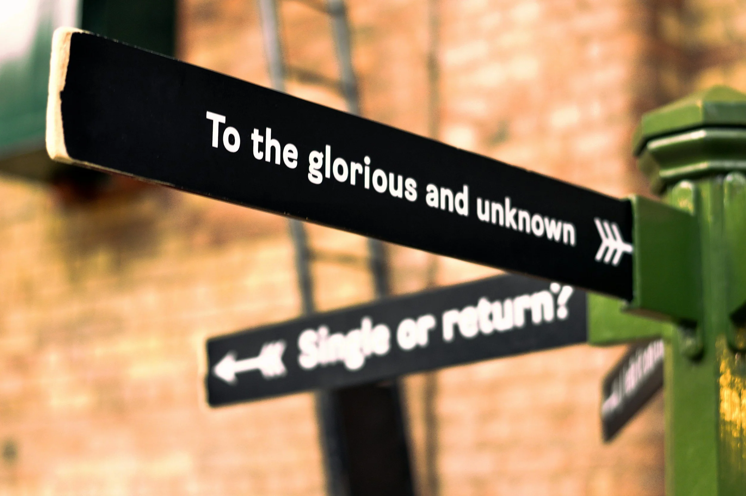 Signpost with the text 'To the glorious and unknown' and another sign pointing to a museum building.