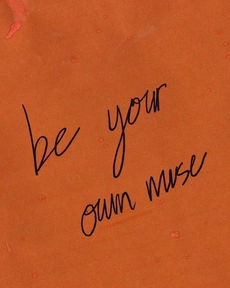 A handwritten note on an orange background that says "be your own muse".