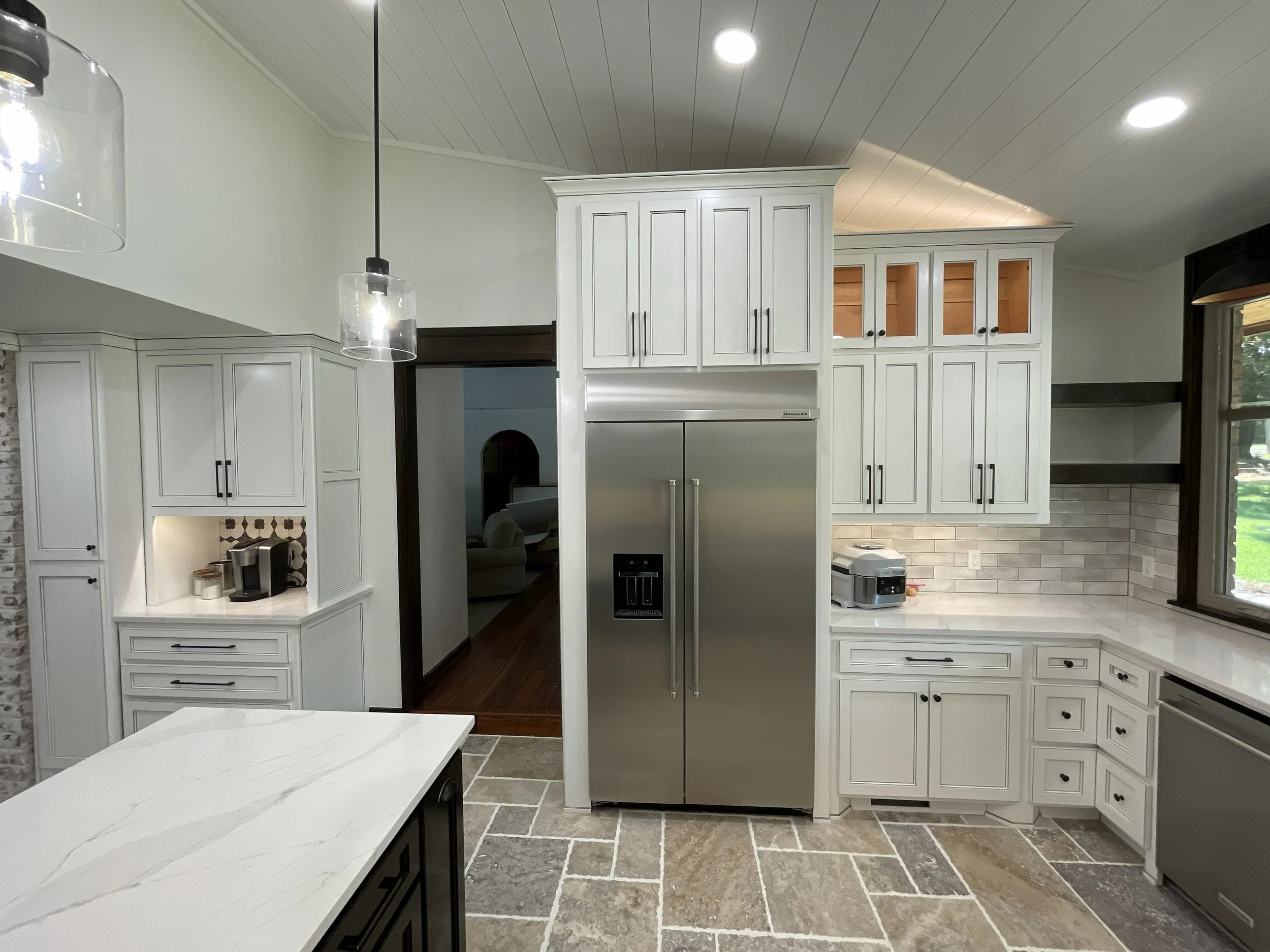 Modern kitchen with white cabinet doors, stainless steel refrigerator, tiled backsplash, and pendant lighting.
