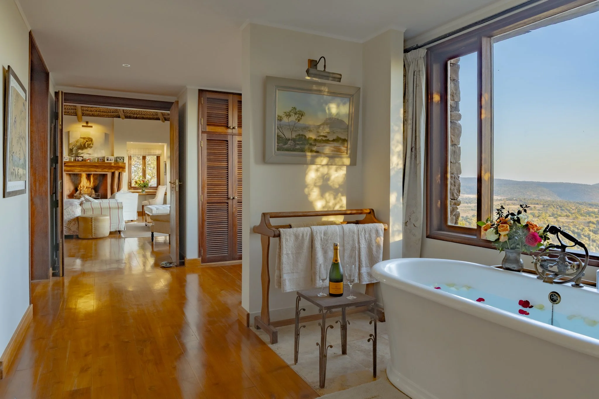Bathtub and champagne and living room with a fire at Laragai House