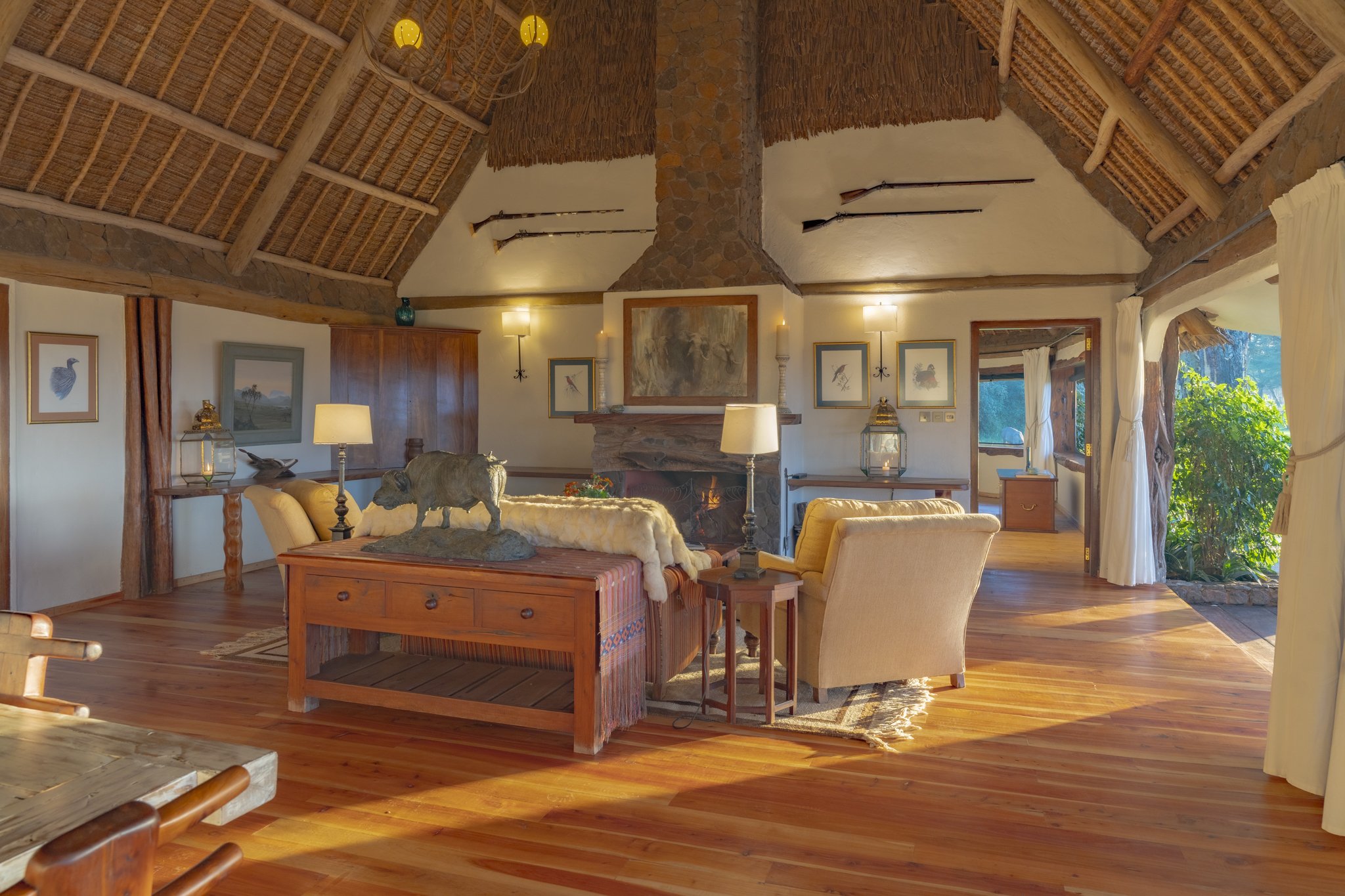 Cozy living room at Sirikoi Cottage at sunset with a roaring fire and candles setting mood with ancient rifles  and paintings decorating the walls.