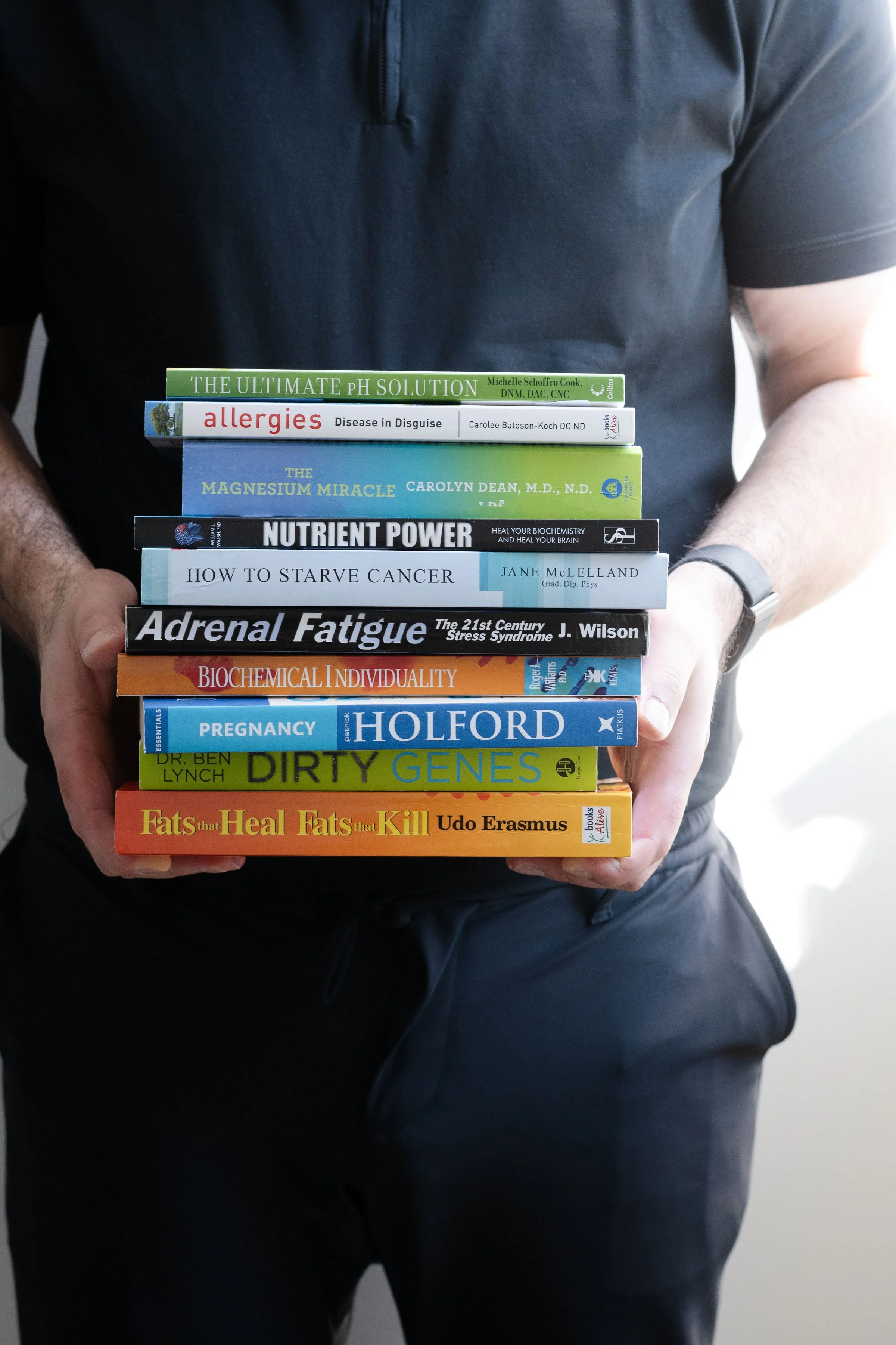 Person in a black shirt holding a stack of books.