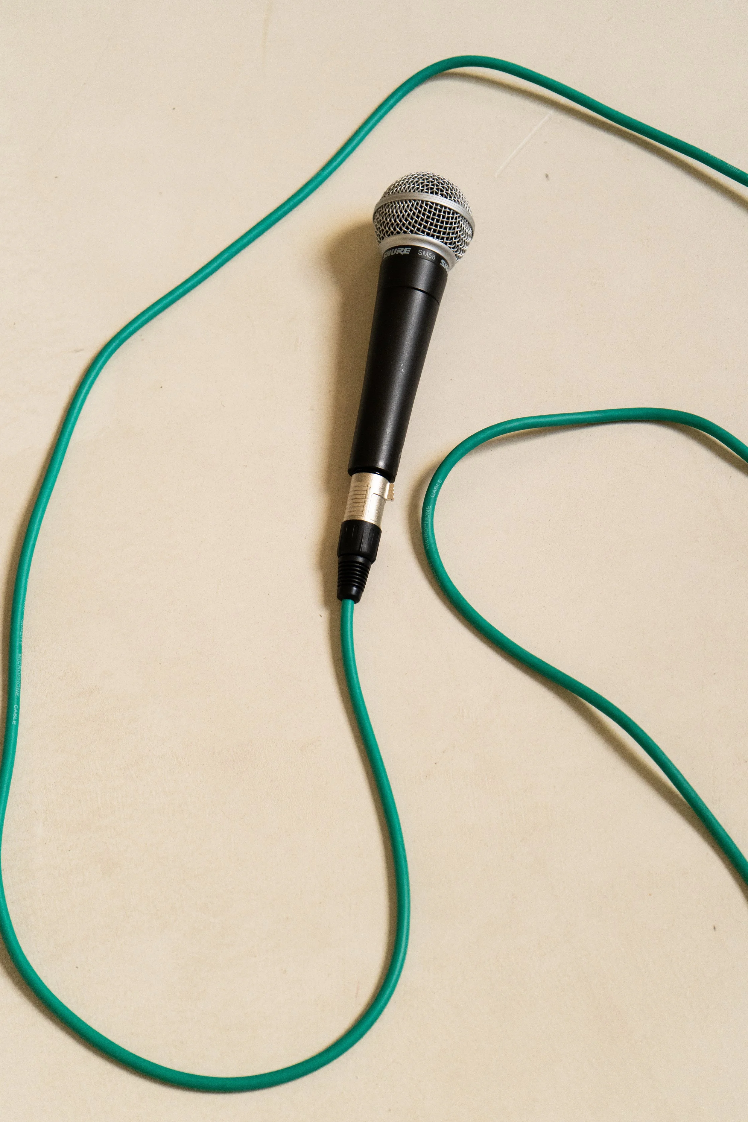 Micrófono de mano sobre una superficie plana con cable verde conectado.