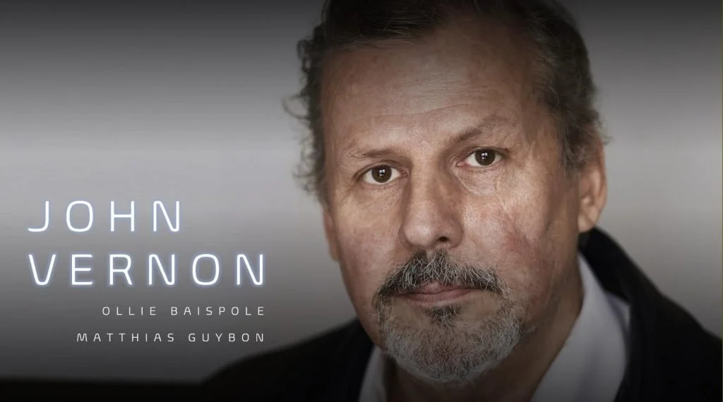 Close-up image of a man with gray hair and beard, looking at the camera, with text overlay of "John Vernon" and names "Ollie Baispole" and "Matthias Guybon."