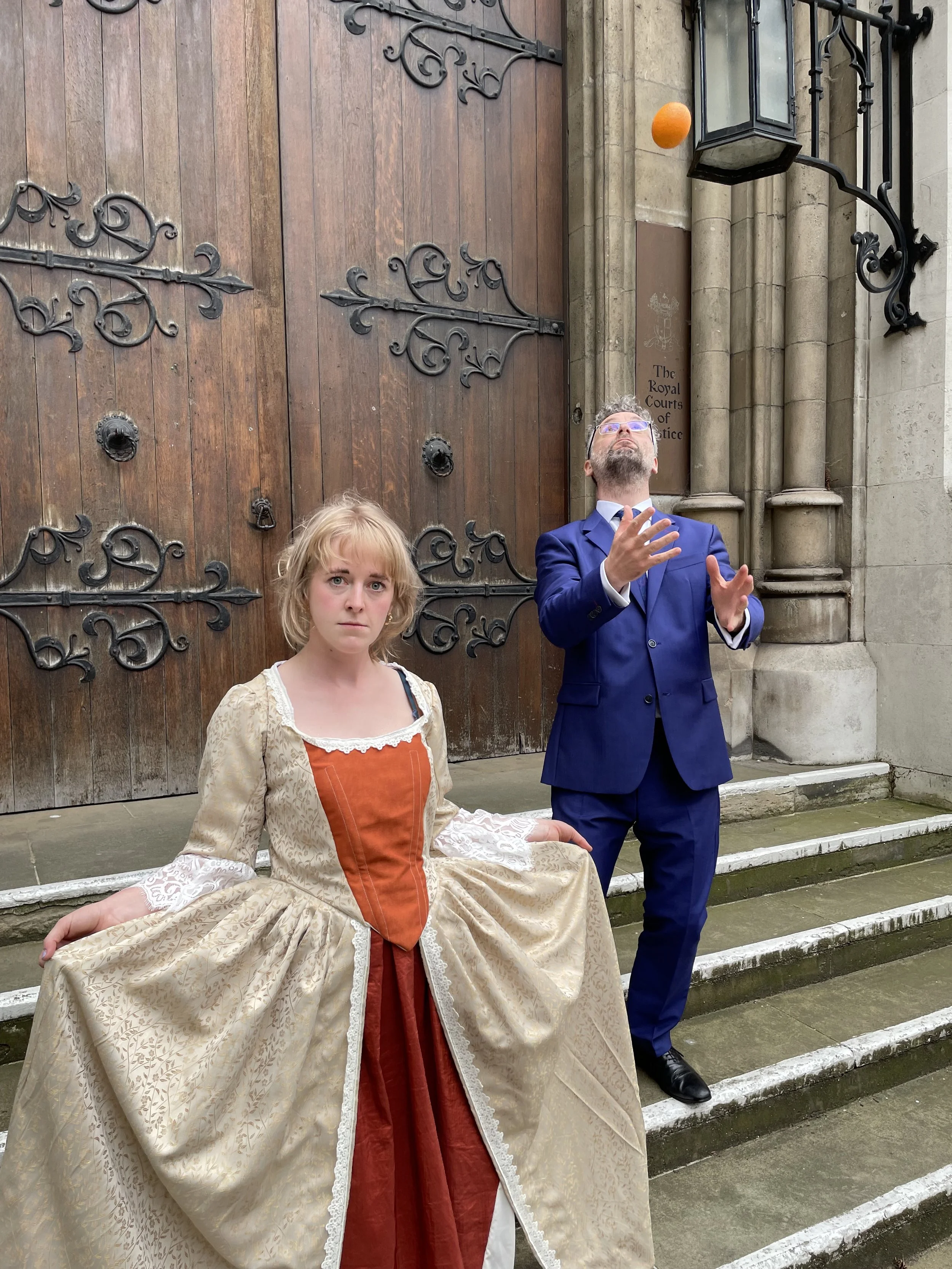 Robert Kingham with Alice Merivale as Nell Gwyn, outside The Royal Courts of Justice. Robert has an orange.