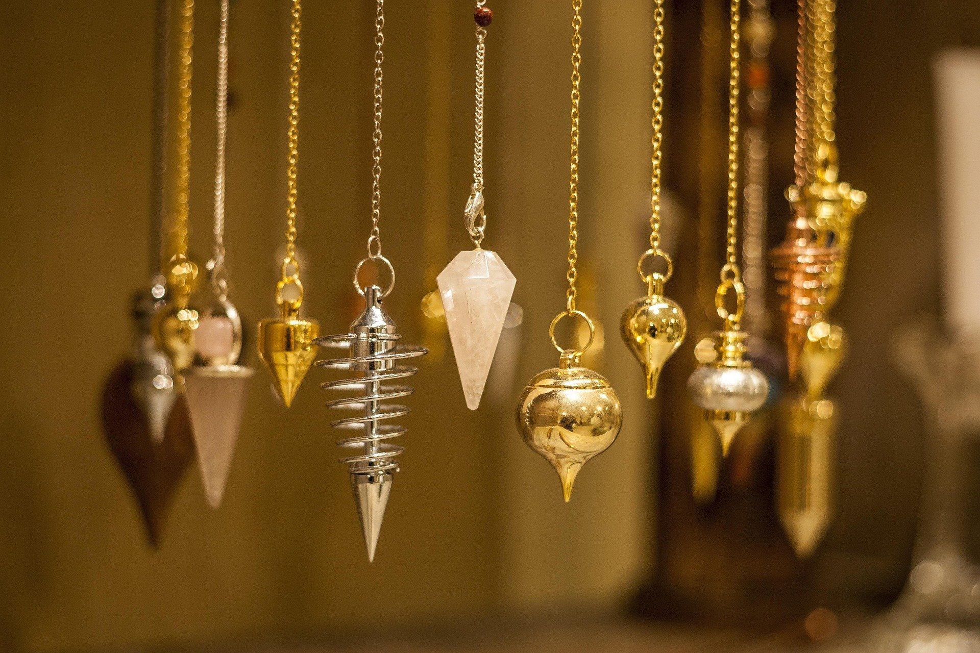 Nahaufnahme von verschiedenen goldenen und silbernen Schmuckketten mit Anhängern, die an einer Stange hängen.