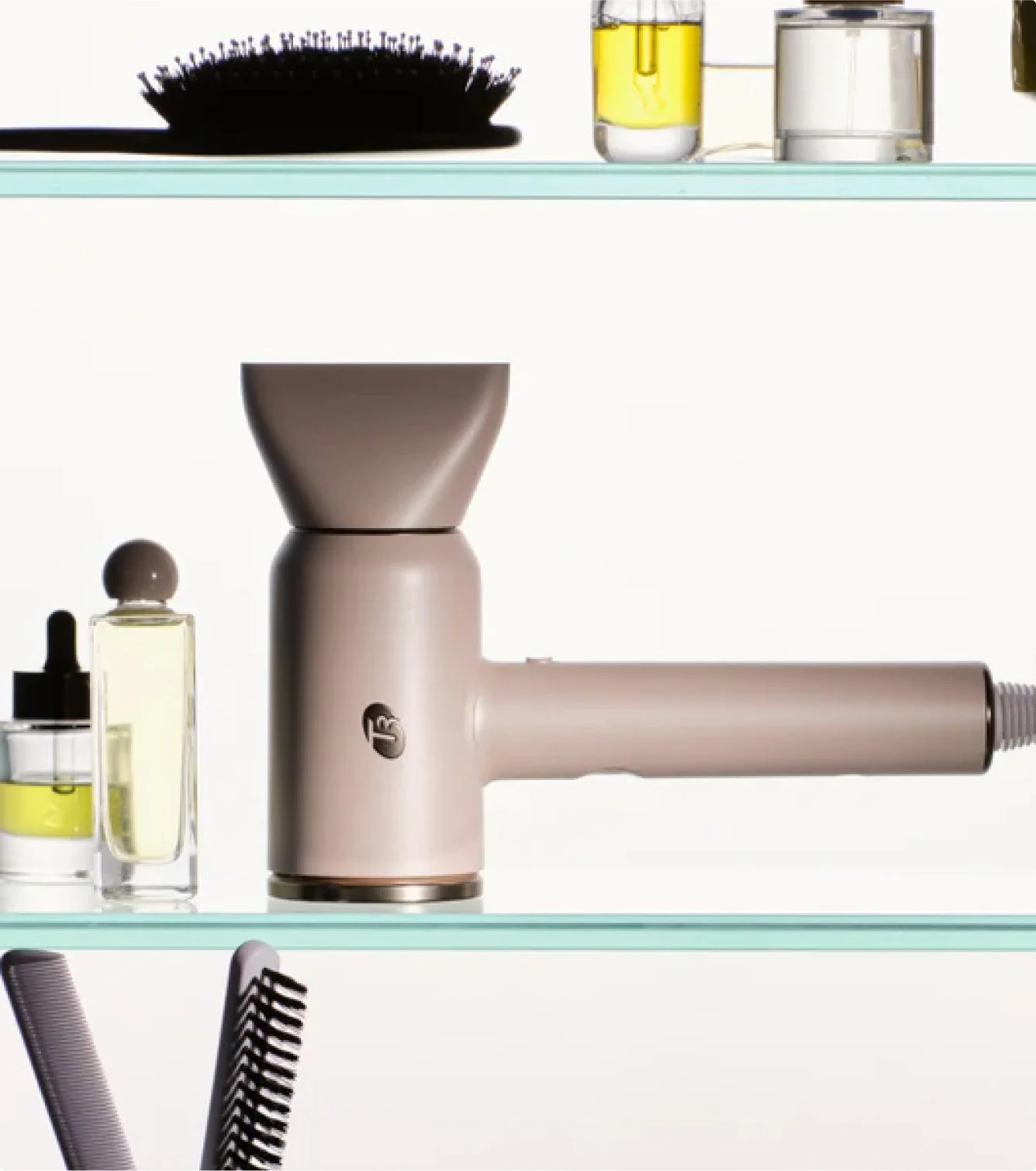 A display shelf with a hairdryer, glass bottles of hair product, and hairbrushes in the background.