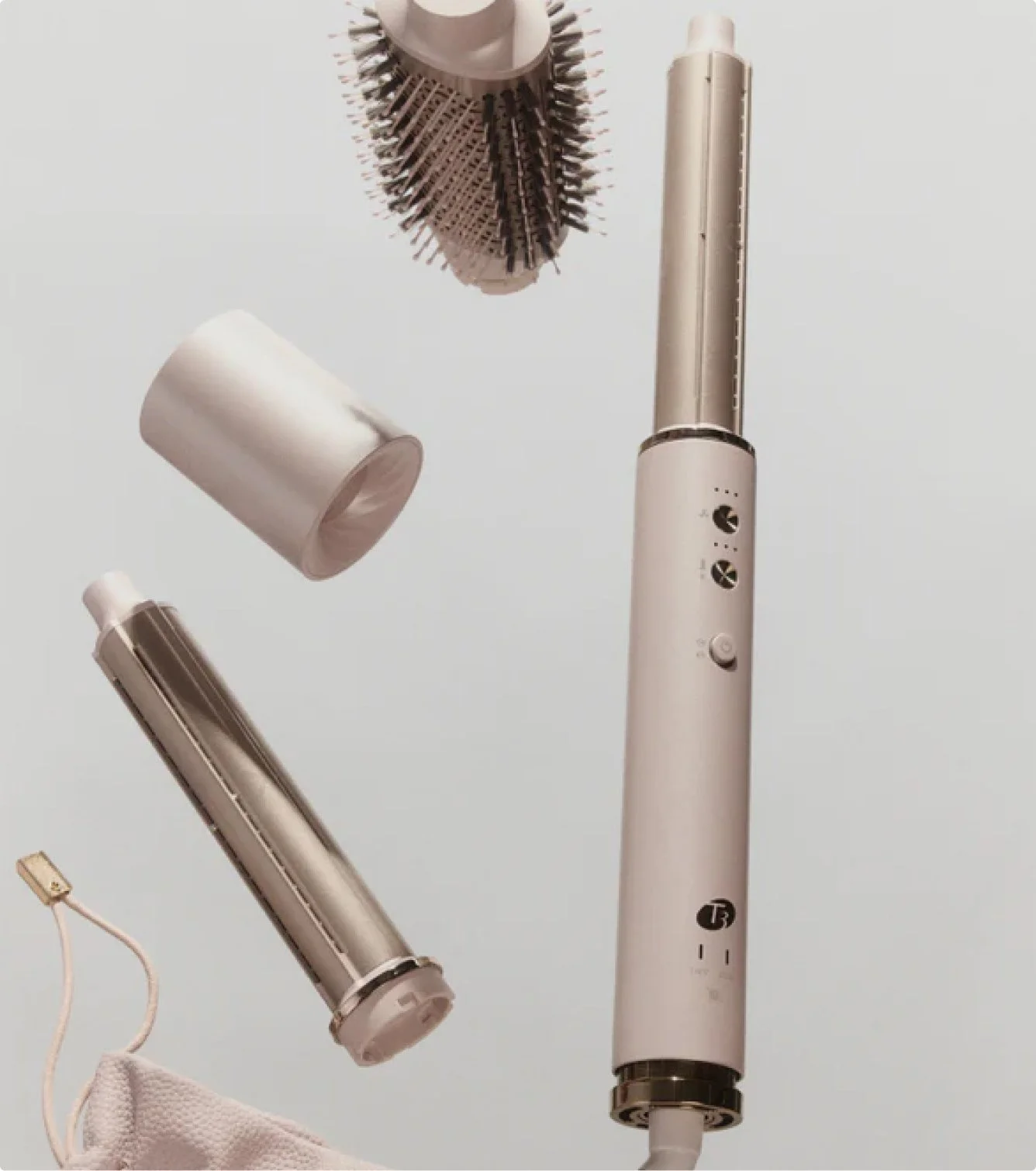 A white and silver electric hair styling brush with control buttons and spinning barrel, several attachments including a round brush and a barrel brush, against a plain background.