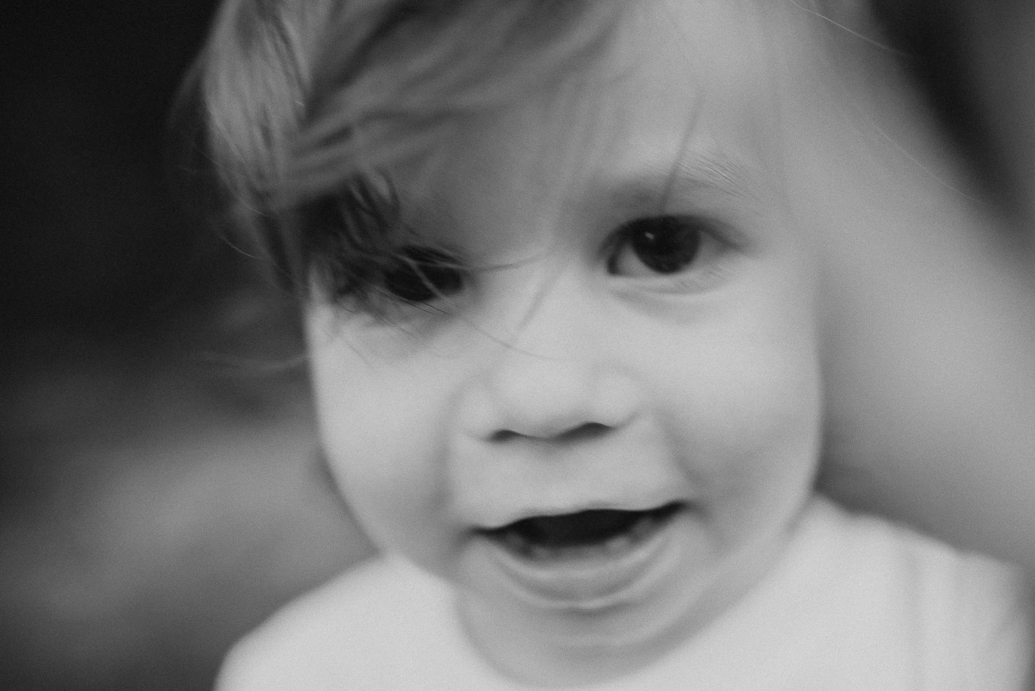 Close-up black and white photo of a child's face, showing a focused expression with wide eyes and slightly parted lips.