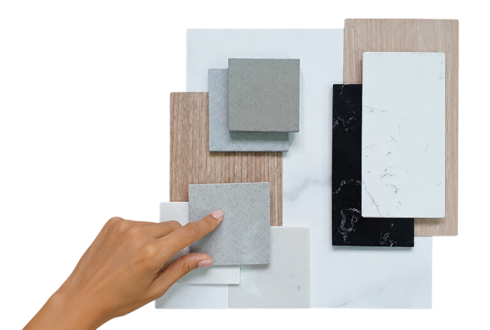 A person's hand selecting a small gray tile from a display of various tile samples in different colors and textures.