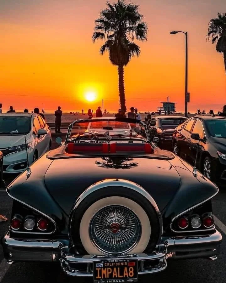 Classic Chevrolet Impala parked near Balboa Fun Zone in Newport Beach, California, during sunset.