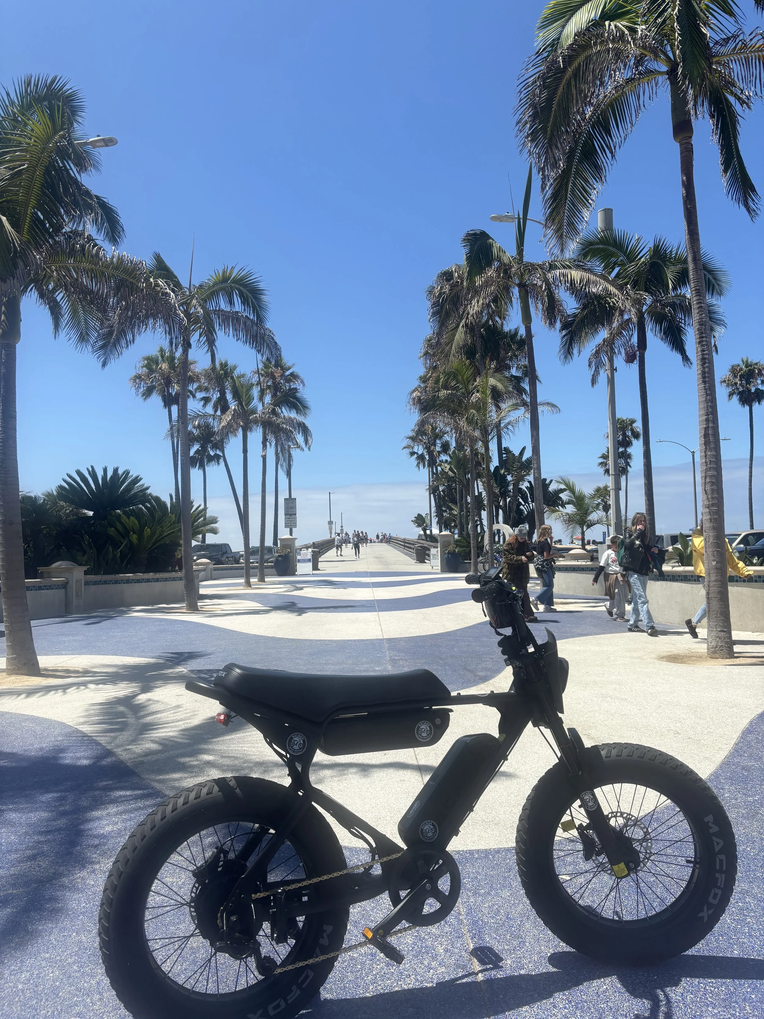 Black Macfox electric bike parked along the Newport Beach boardwalk near the Balboa Peninsula.