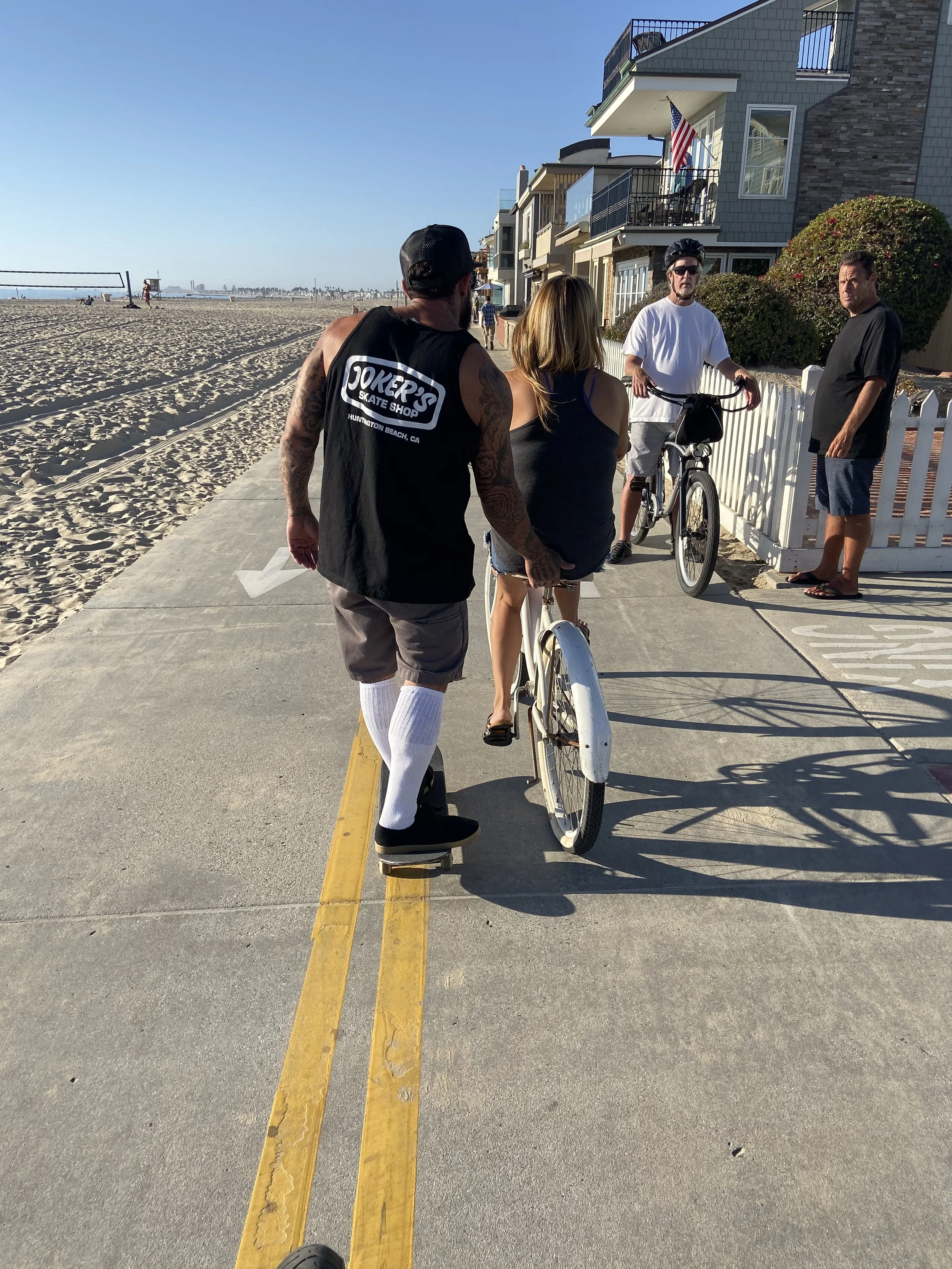 People walking and riding bikes along the Newport Beach boardwalk on the Balboa Peninsula.