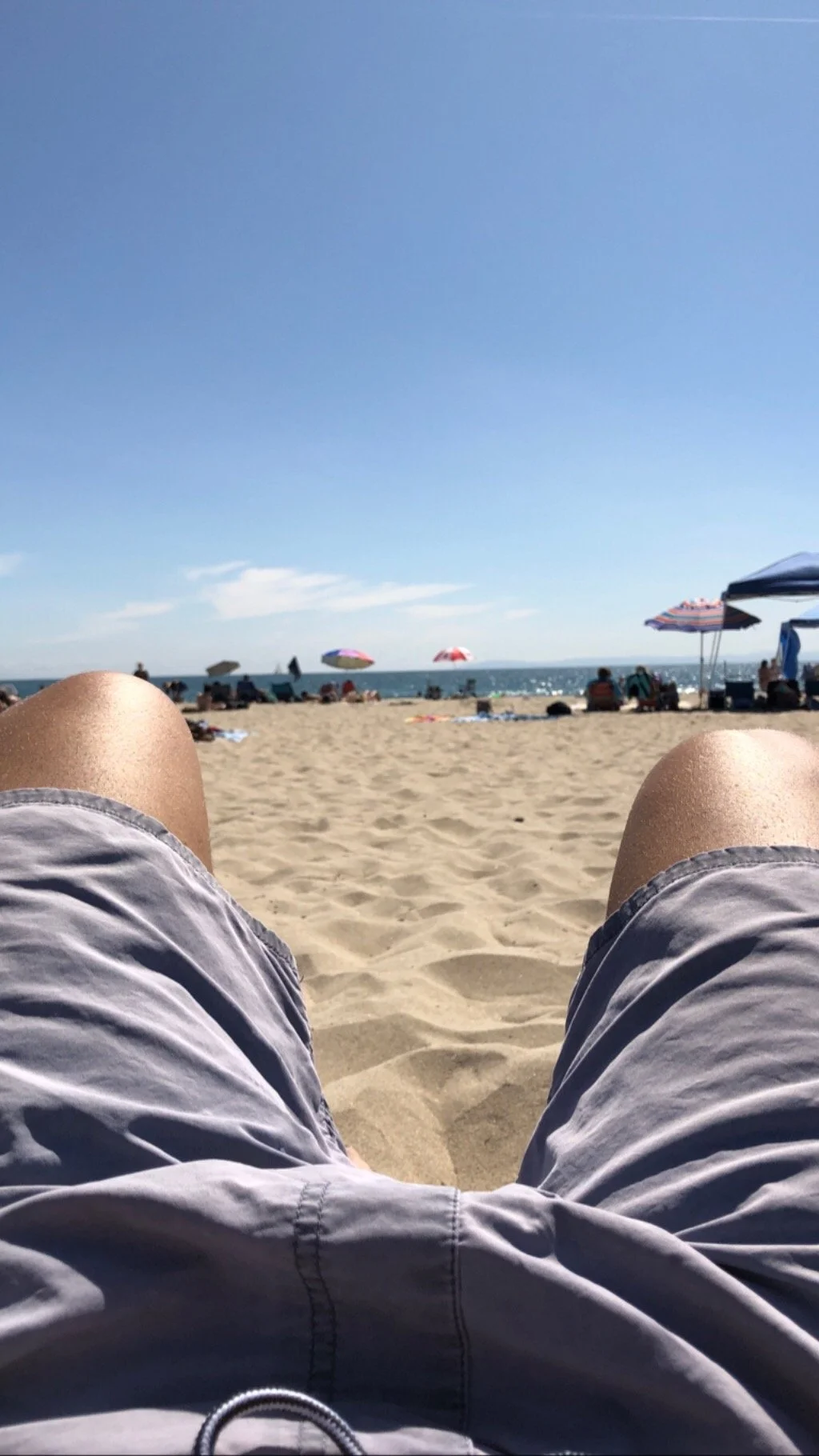 Person relaxing on Newport Beach, California, enjoying the ocean near the Balboa Peninsula on a sunny day.