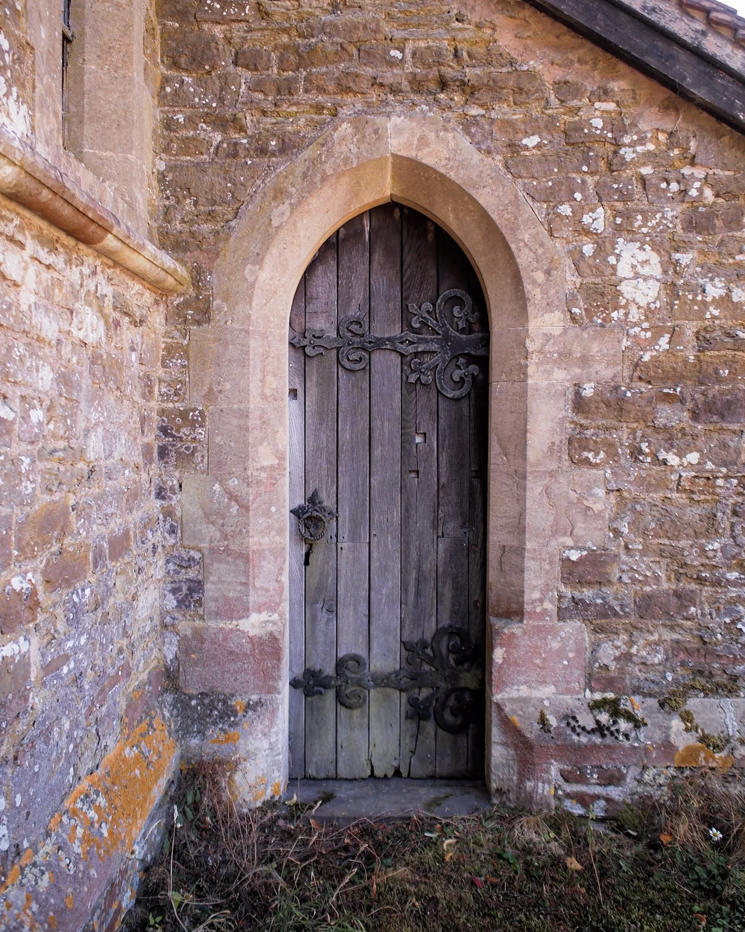 Stone walls with lichen, a small doorway with iron hinges and handle