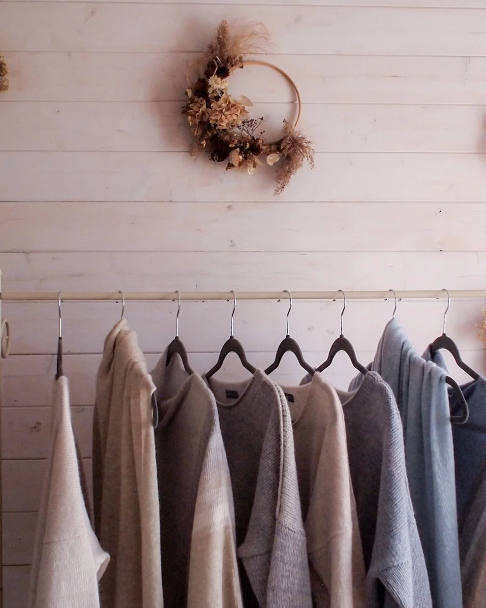 A rail with knitted garments and scarves, shades of soft blue and neutrals