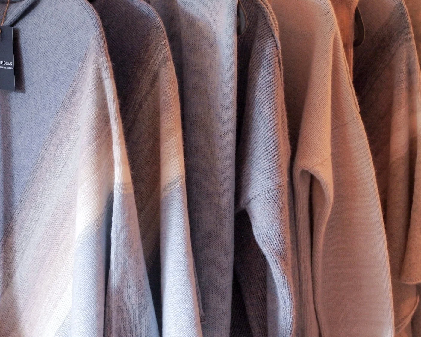 Knitwear hanging on a rail. Soft blues and neutrals.