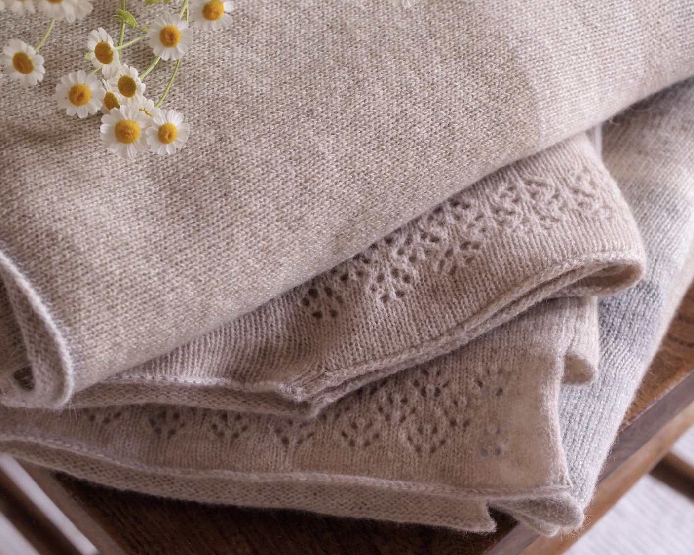 soft folded knits on a wooden chapel chair with feverfew on the top