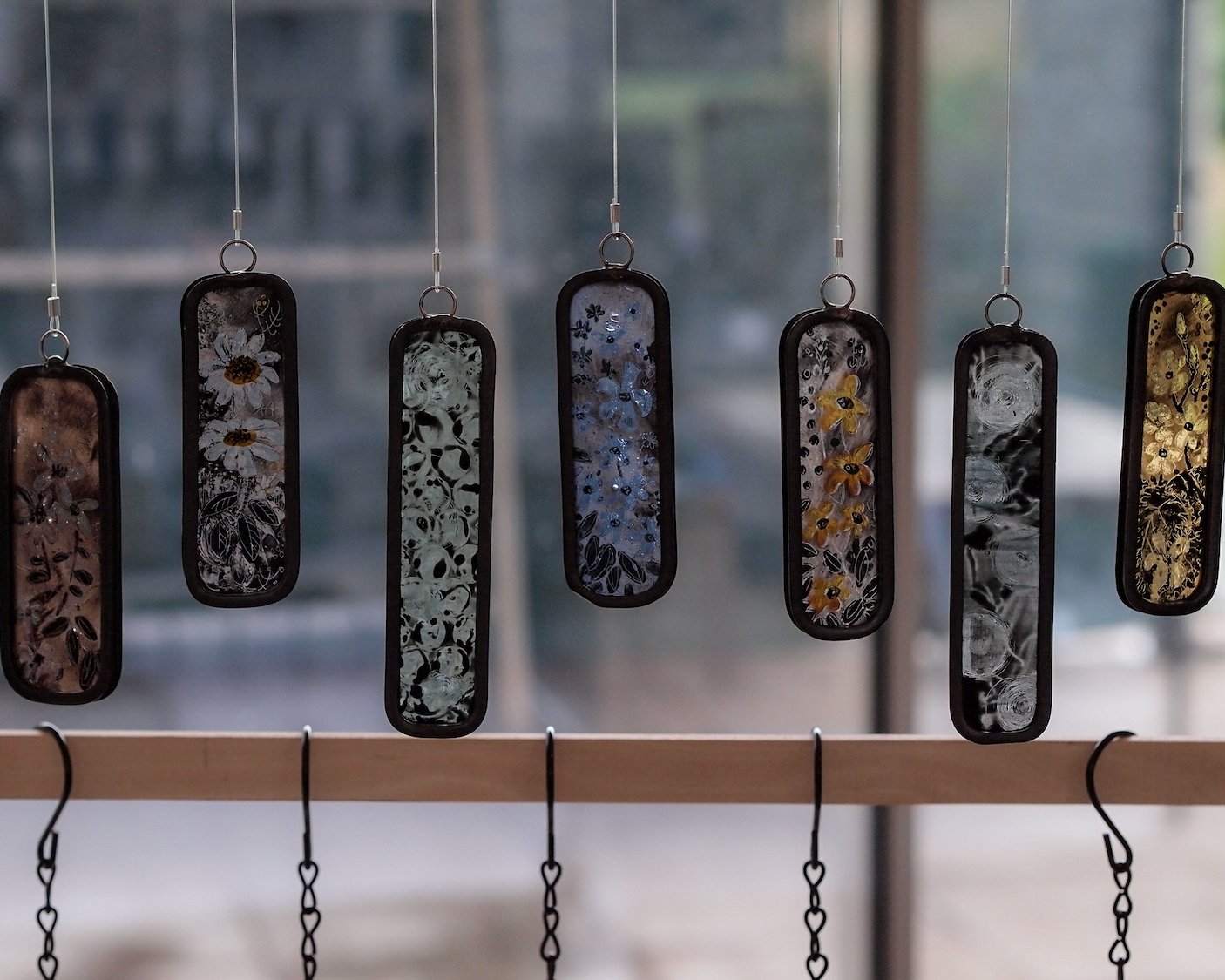 7 small glass pendulums by luci clark. designs include daisies, leaves and forget me nots