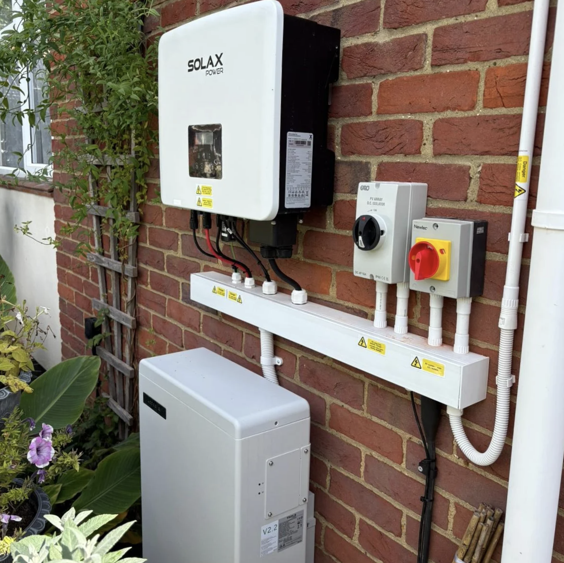 Solar power inverter system installed on a brick wall, with monitoring and control panels, and electrical wiring connected to it.