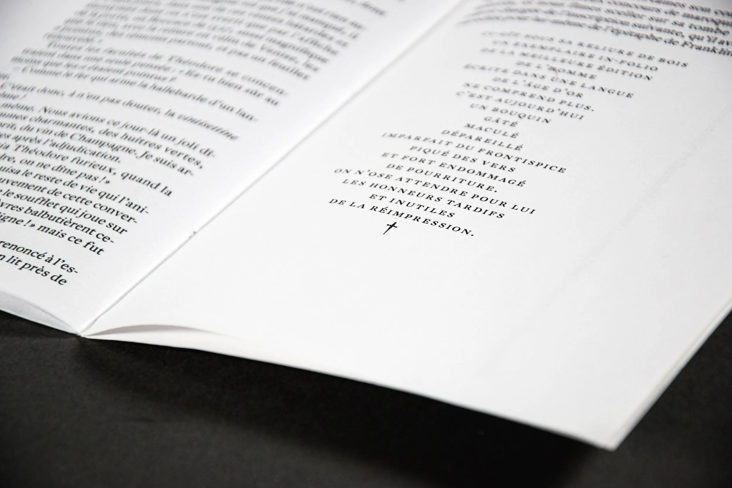 Page d'un livre ouvert avec le texte en français, posé sur une surface noire. La photo est floue, surtout sur la gauche, et se concentre sur la partie droite du livre.