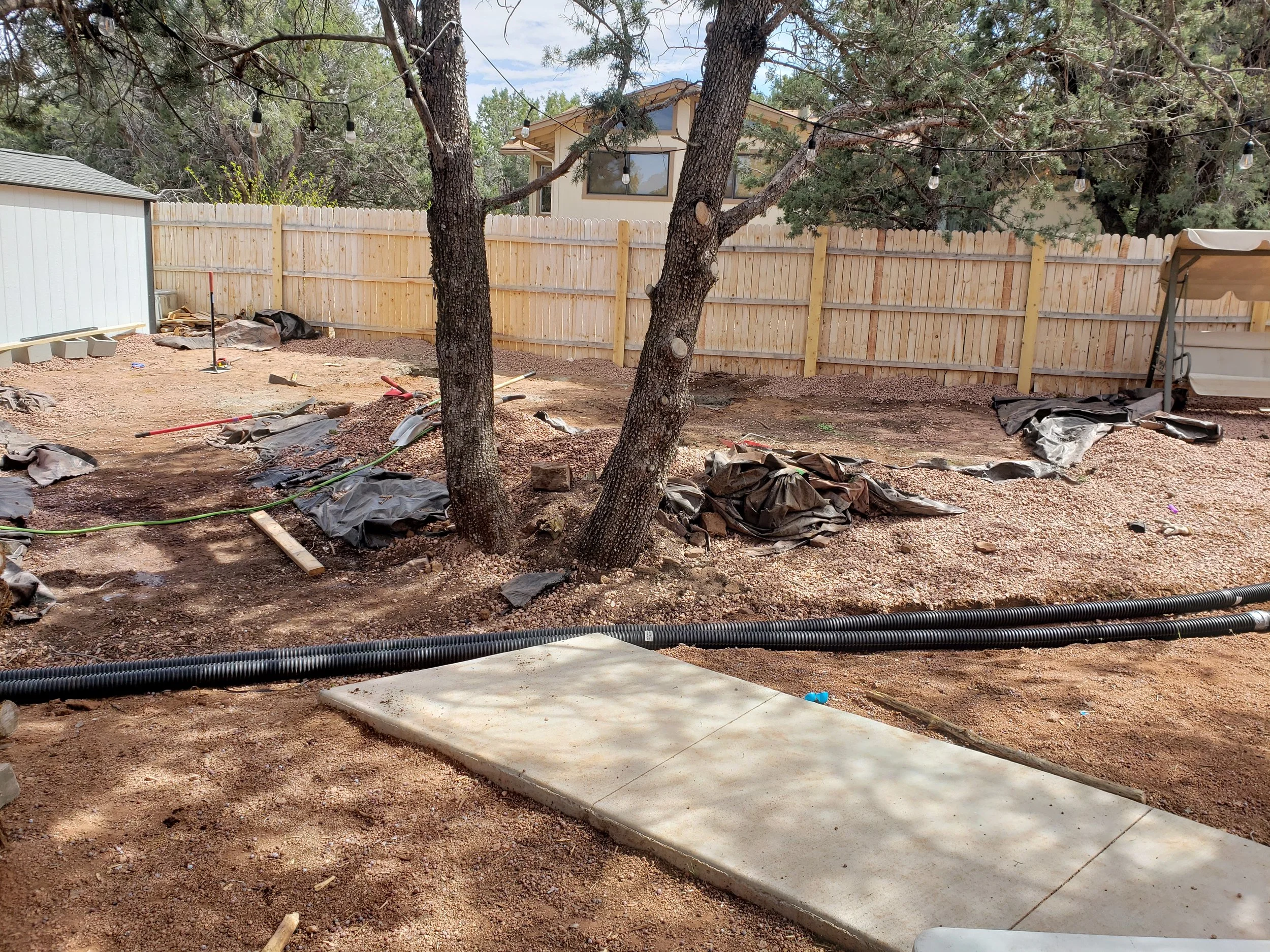Gator Home Services- Payson- A backyard that is in the beginning of a project with pipes going through and piles of dirt and trash