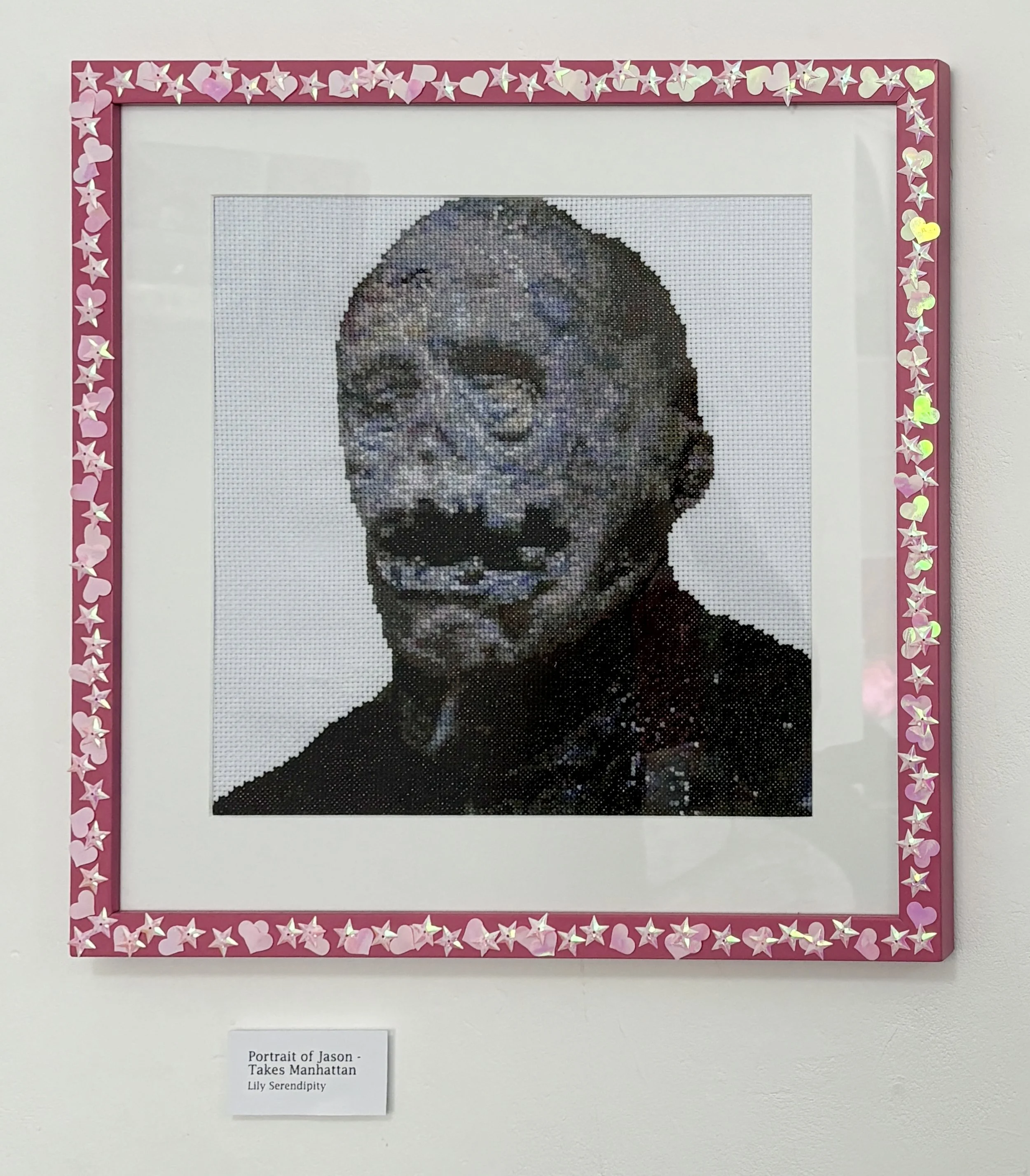 Cross-stitch portrait of a horror character framed with pink border decorated with heart and star-shaped embellishments.
