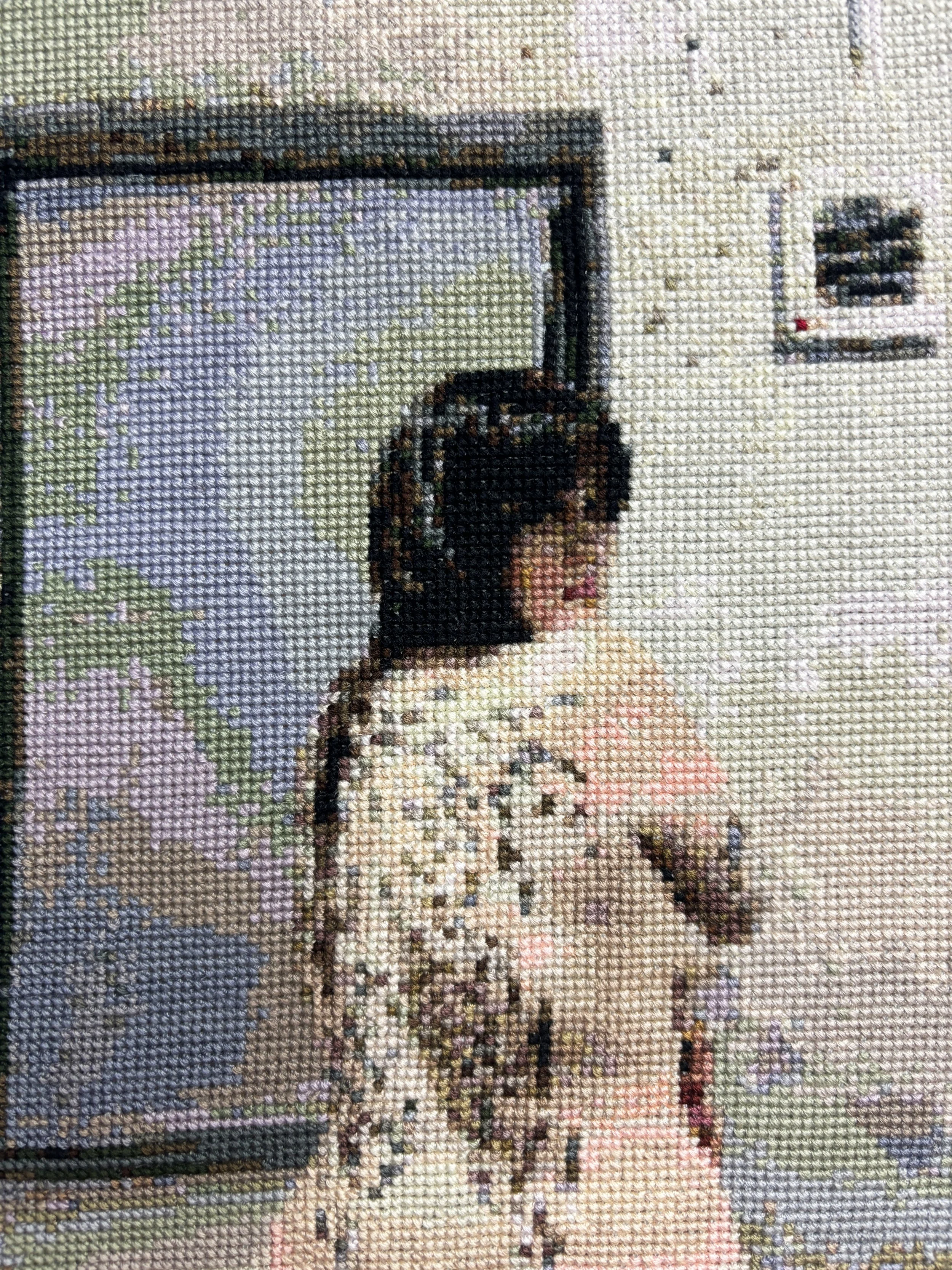 Close-up of a cross-stitch embroidery artwork depicting a nude woman.