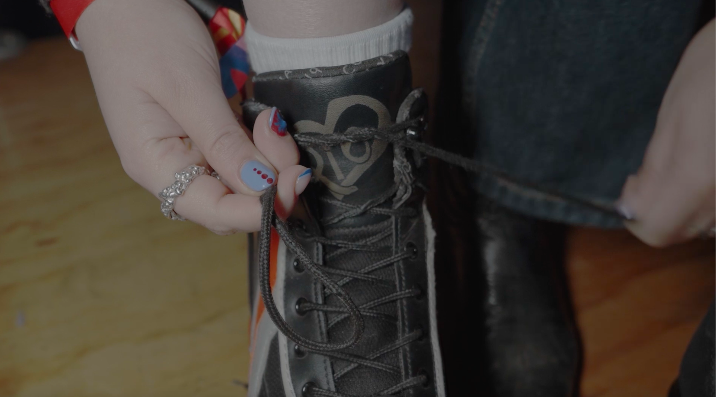 A person tying the laces of a black and gray Nike high-top sneaker.