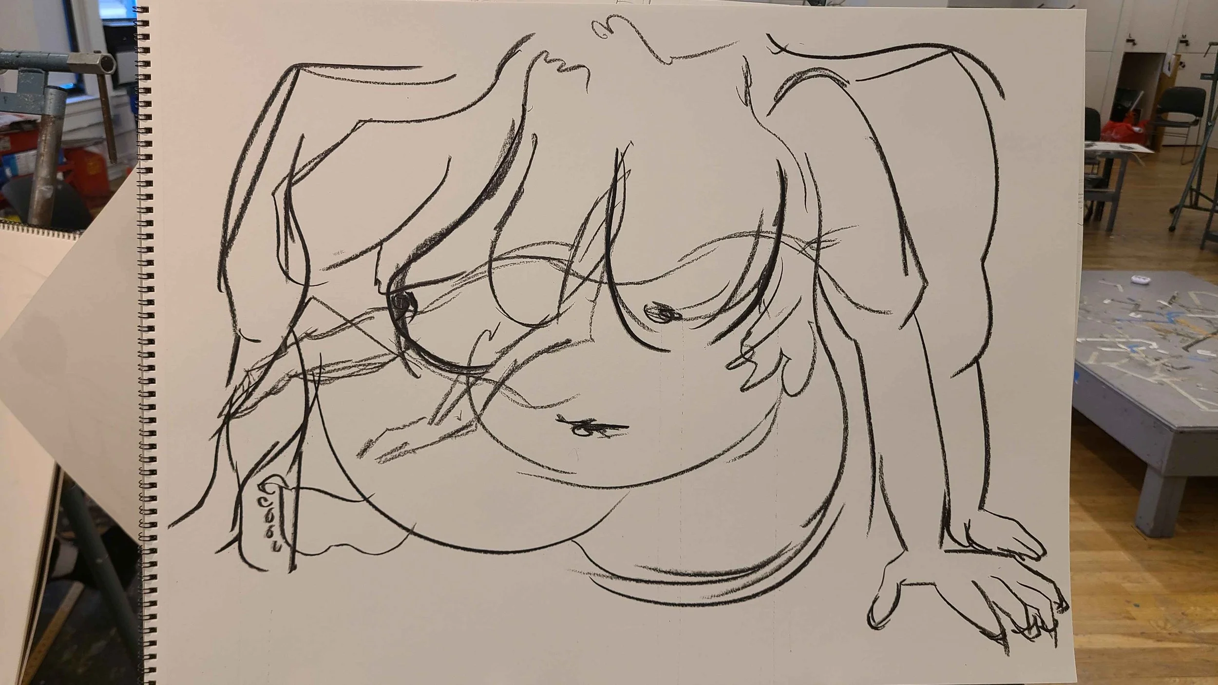 A sketch of a woman's face with long hair, drawn with black lines on a white piece of paper. The sketch is displayed on a stand in an indoor space.