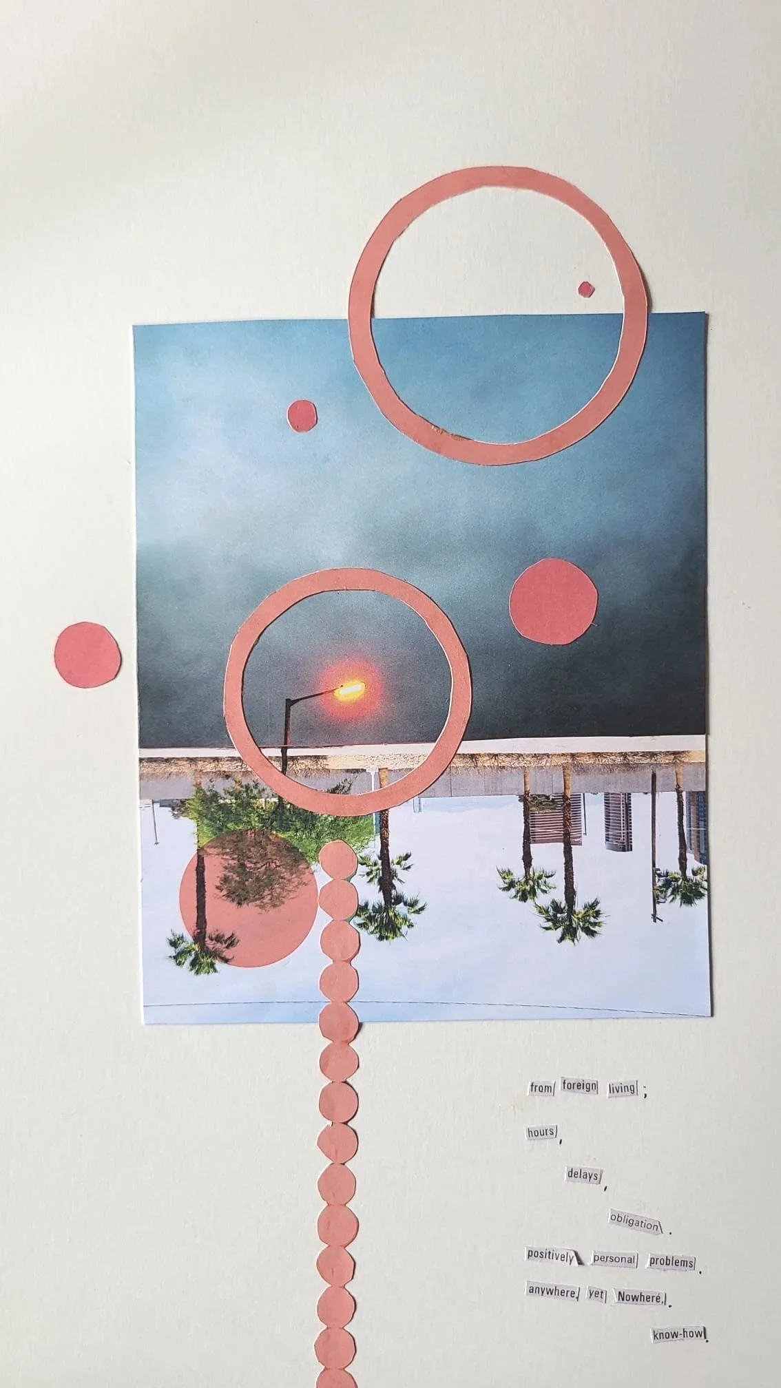 A collage on a white wall featuring a photograph of a beach with palm trees and a boardwalk, overlaid with pink paper circles forming a vertical line, pink paper rings, and small pink circles. There is a strip of text at the bottom with words such as