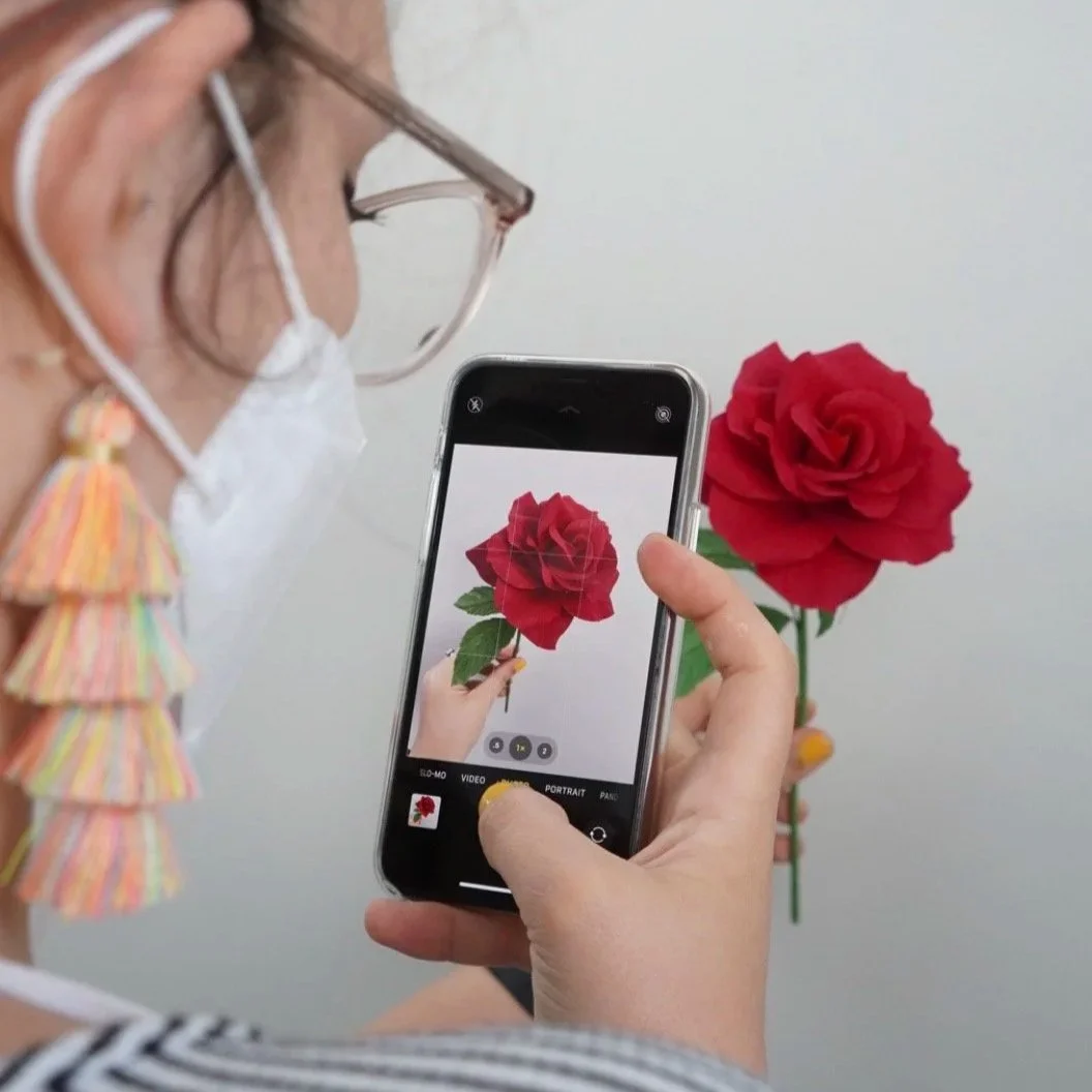 Merremade student taking a photo of a handmade red paper rose with a phone during a in-person workshop in Seoul, Korea.